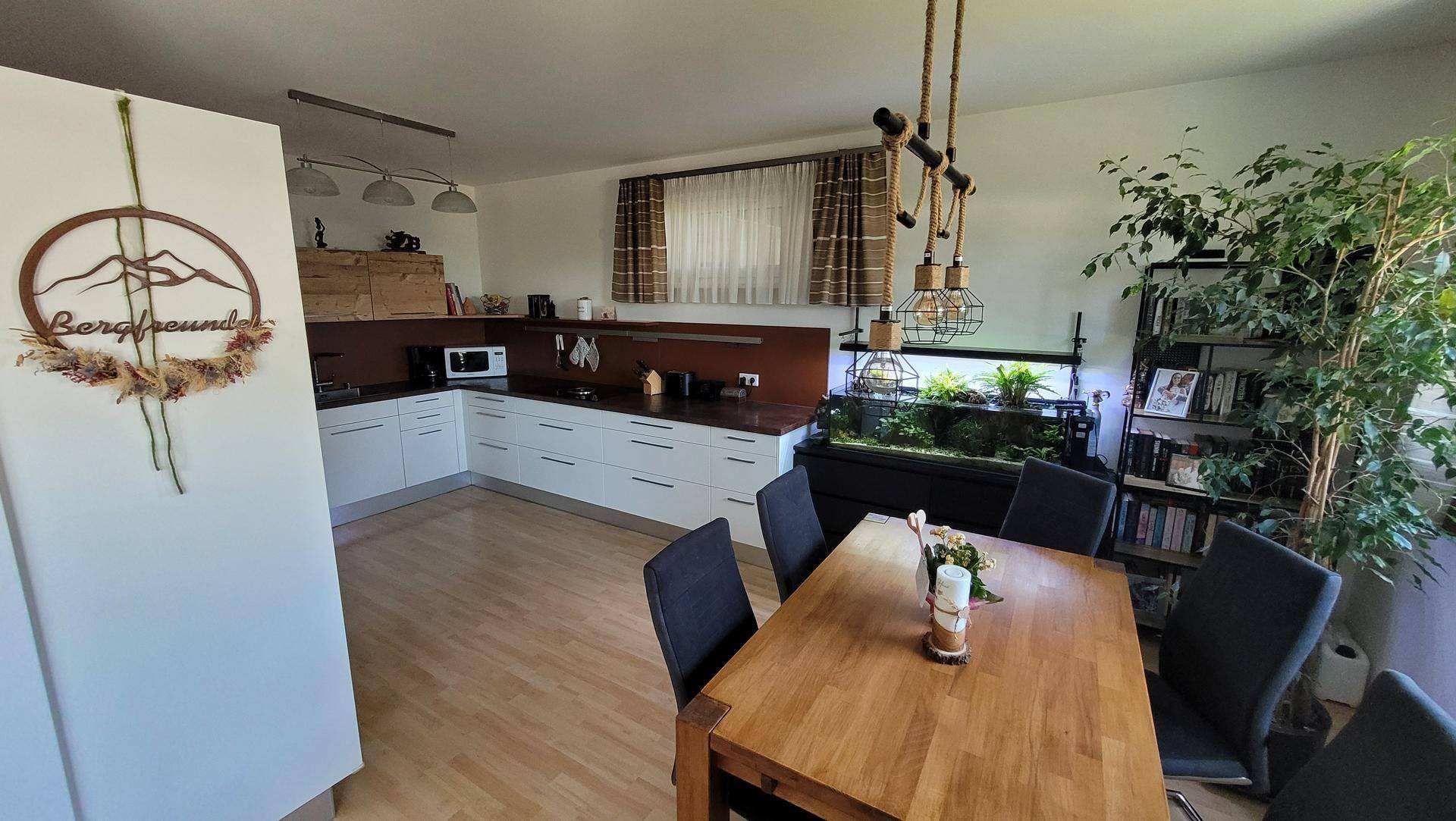 Offene Küche mit Essbereich, modernem Design, weißen Schränken und einem großen Esstisch.