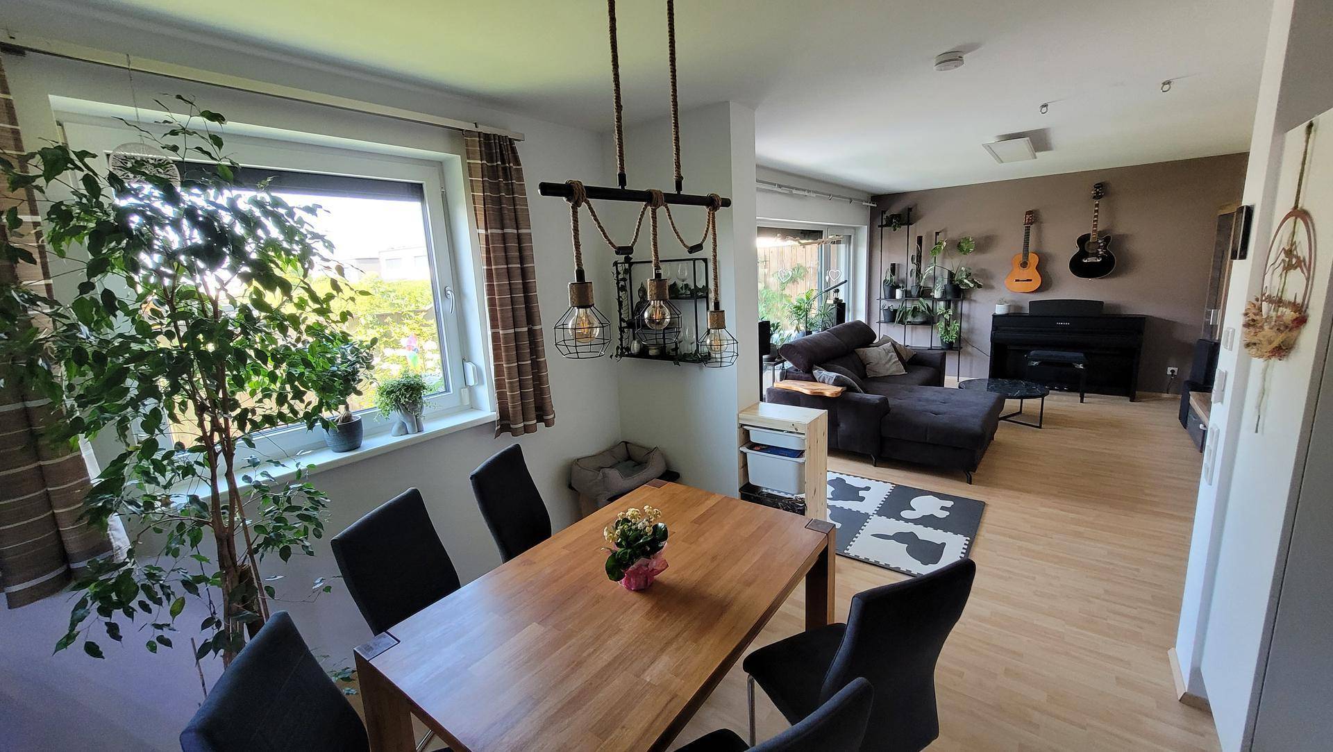 Offener Wohn- und Essbereich mit Holztisch, Parkettboden und Blick auf den angrenzenden Wohnbereich.