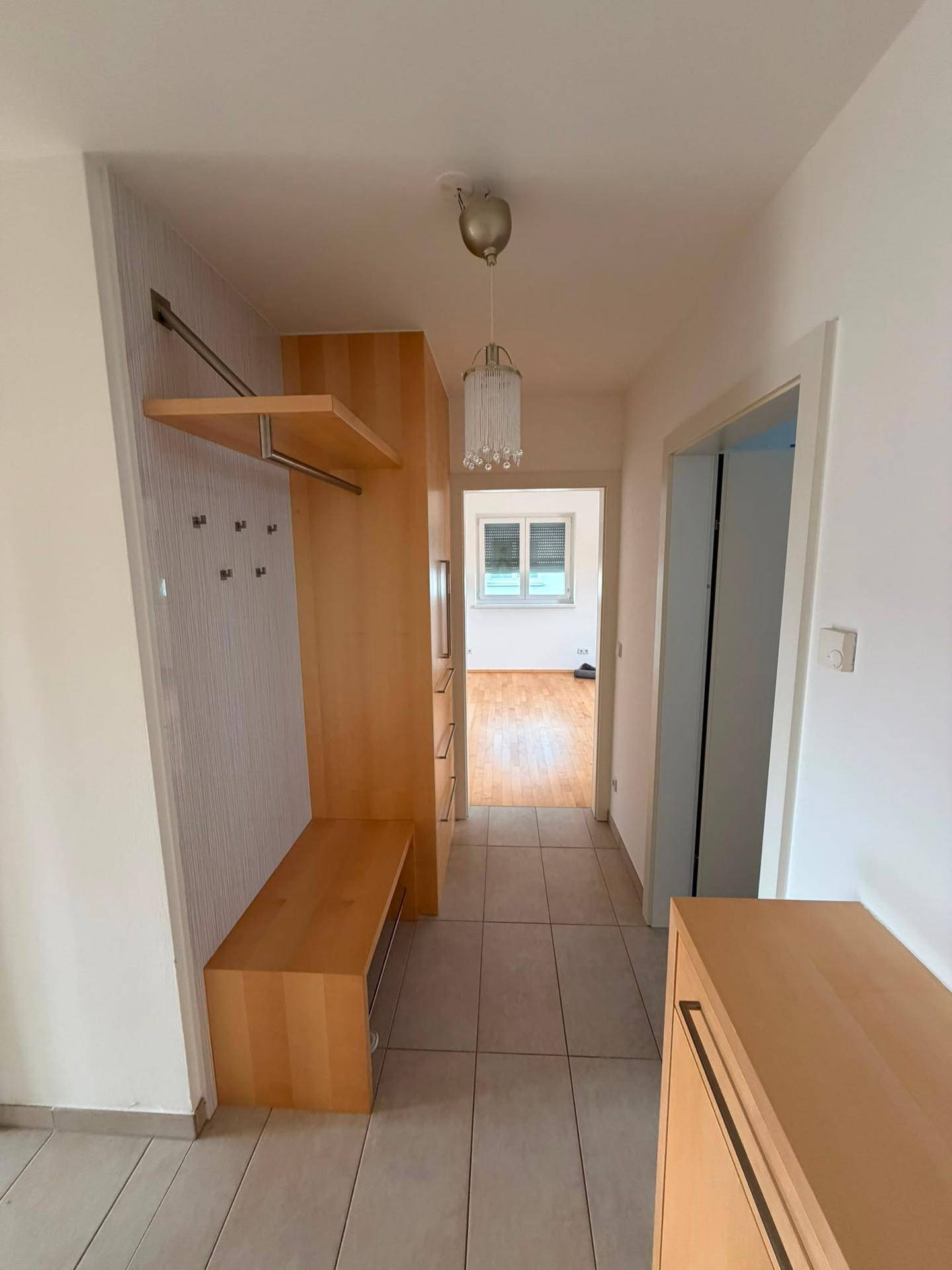 Heller Eingangsbereich mit praktischer Garderobe und Holzmöbeln, führt zu weiteren Räumen.