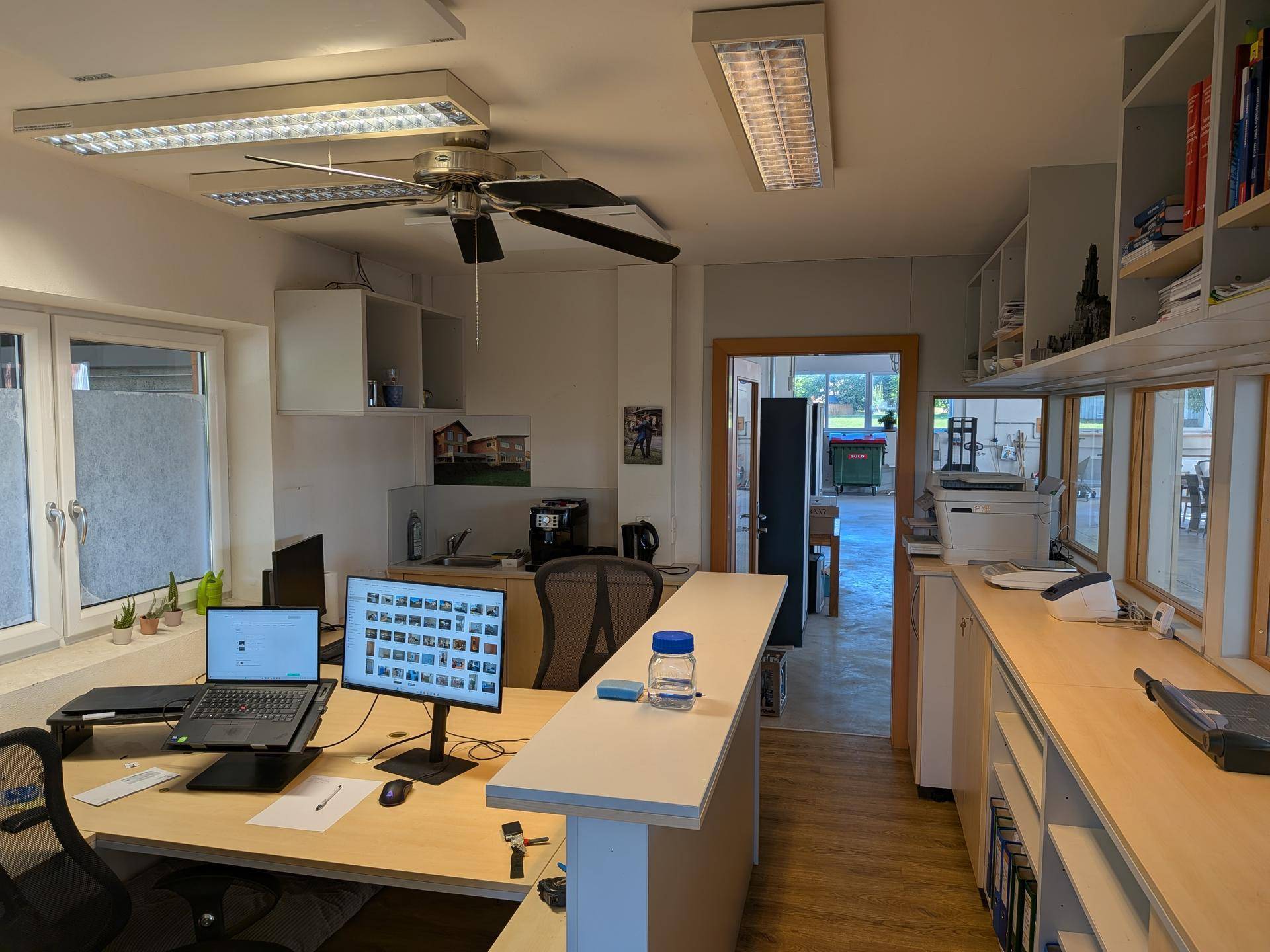 Helles Büro mit Schreibtisch, Computer und Deckenventilator, bietet eine angenehme Arbeitsumgebung.