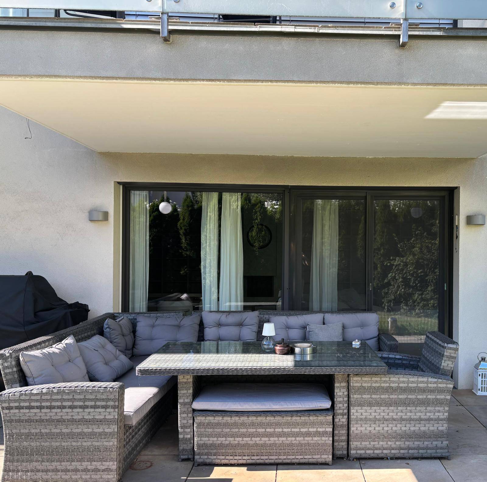 Gemütliche überdachte Terrasse mit Rattan-Lounge-Möbeln und Grillbereich für entspannte Stunden.