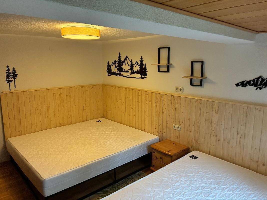 Schlafzimmer mit zwei Matratzen auf dem Boden, Holztäfelung und alpiner Wanddekoration.