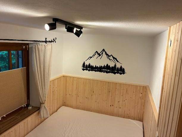 Gemütliches Schlafzimmer mit Holzwänden und einem stilvollen Bergmotiv als Wanddekoration.