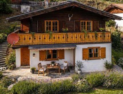 Traditionelles Chalet mit Holzbalkon und einer charmanten Terrasse mit Sitzgelegenheiten im Freien.