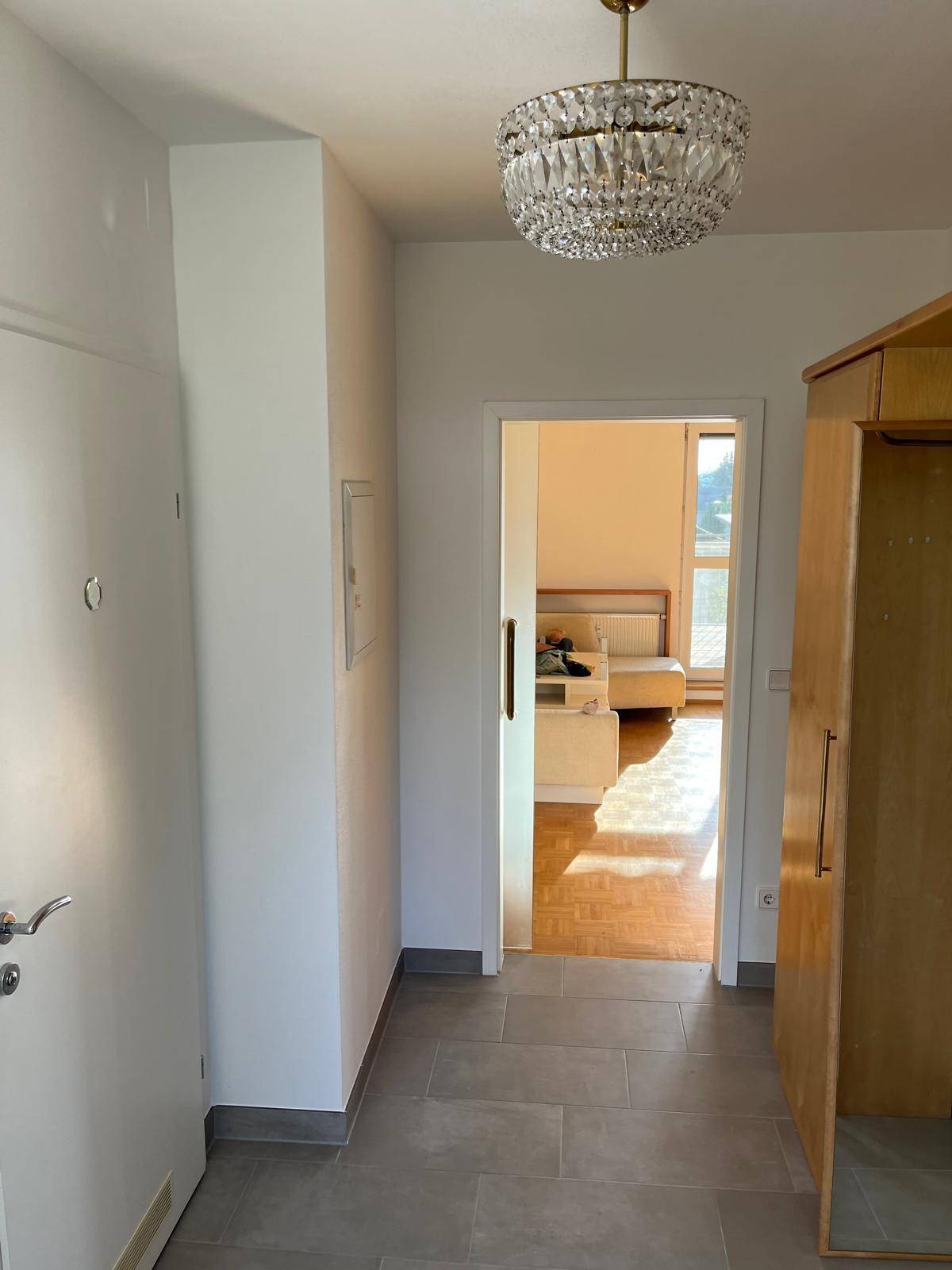 Heller Flur mit modernen Fliesen und Blick in ein sonniges Zimmer.