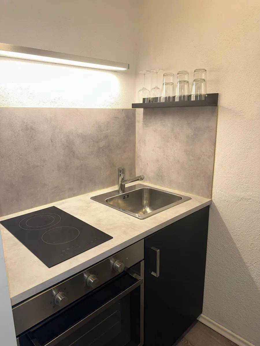 Kompakte Küchenzeile mit Spüle, Induktionskochfeld und Backofen, ideal für kleine Wohnungen.