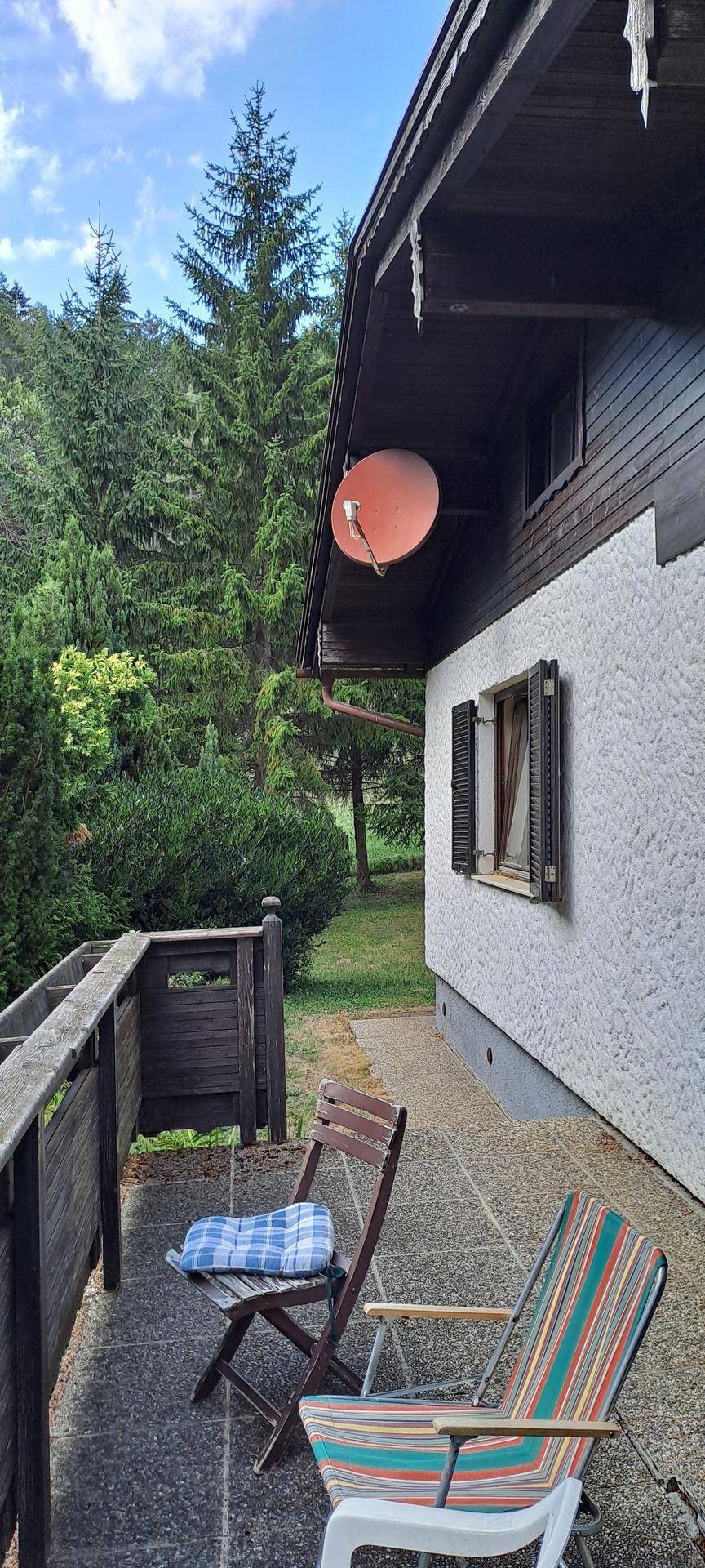 Balkon mit Sitzgelegenheiten und Blick auf die umliegenden Bäume und Natur.