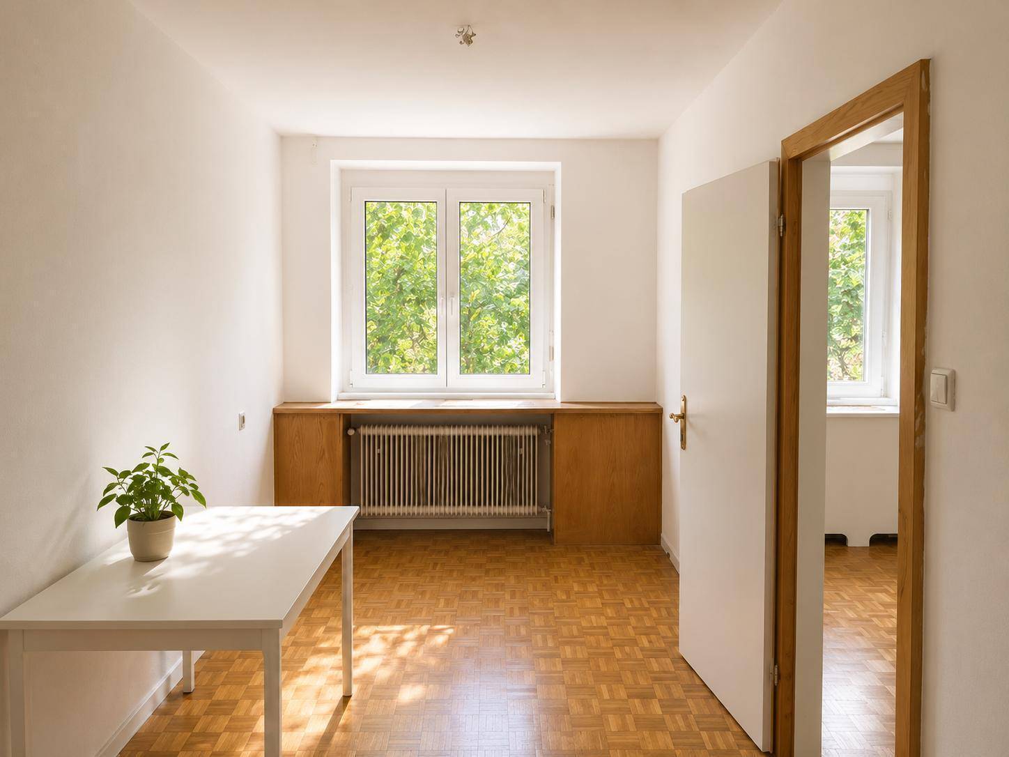 Freundliches Zimmer mit Parkettboden und Blick ins Grüne, ideal als Schlaf- oder Arbeitszimmer.