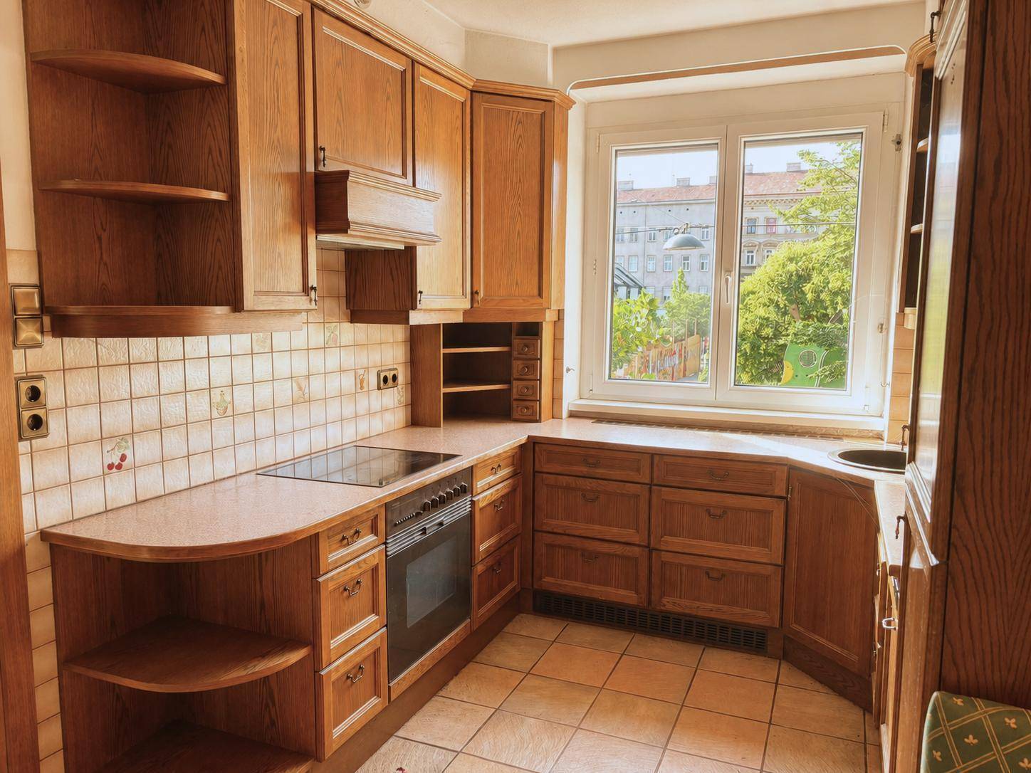 Traditionelle Holzküche mit Einbaugeräten, Fliesenboden und Fensterblick auf die Umgebung.