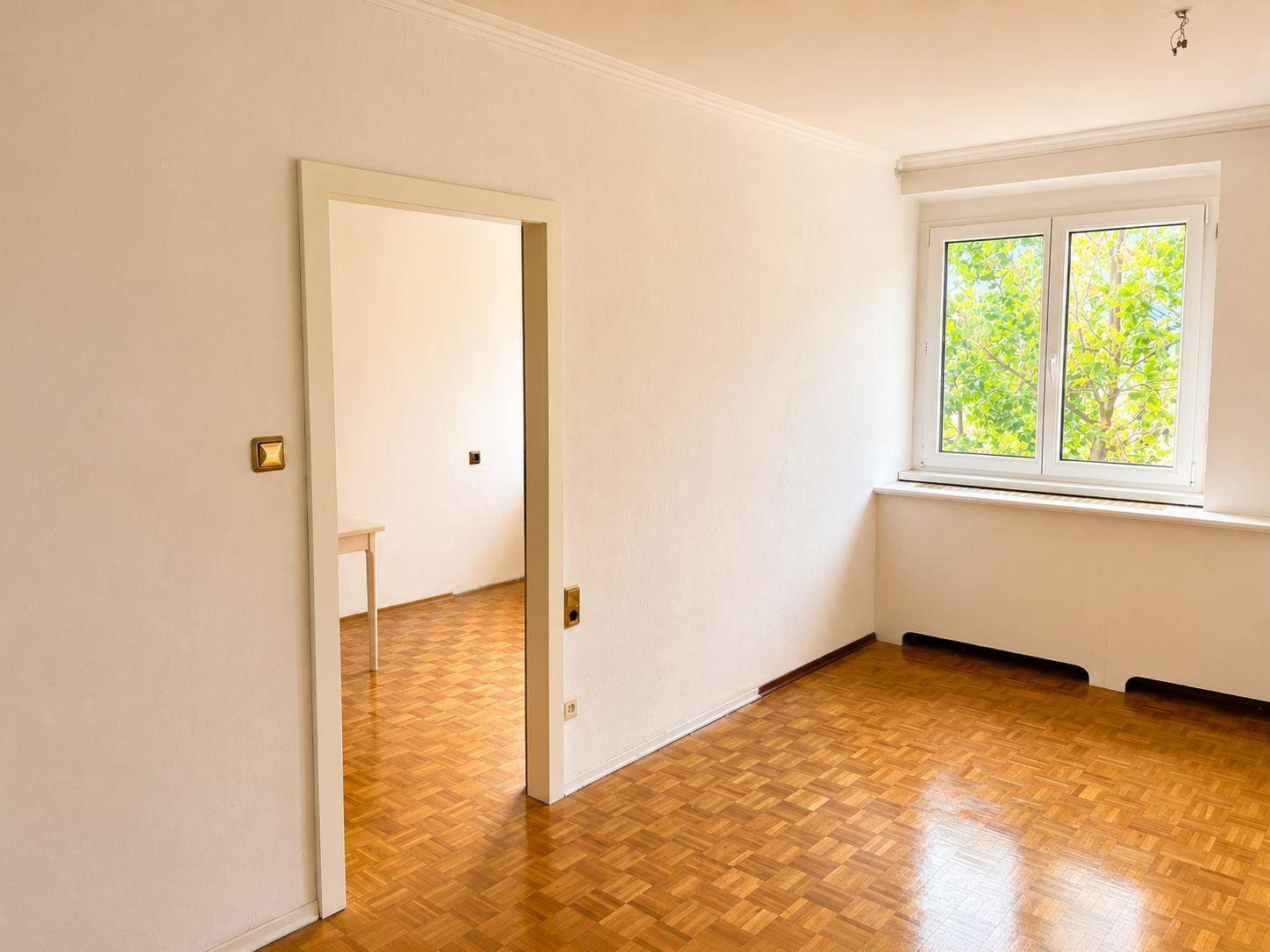 Helles Zimmer mit Parkettboden und Blick ins Grüne, ideal für individuelle Gestaltung.