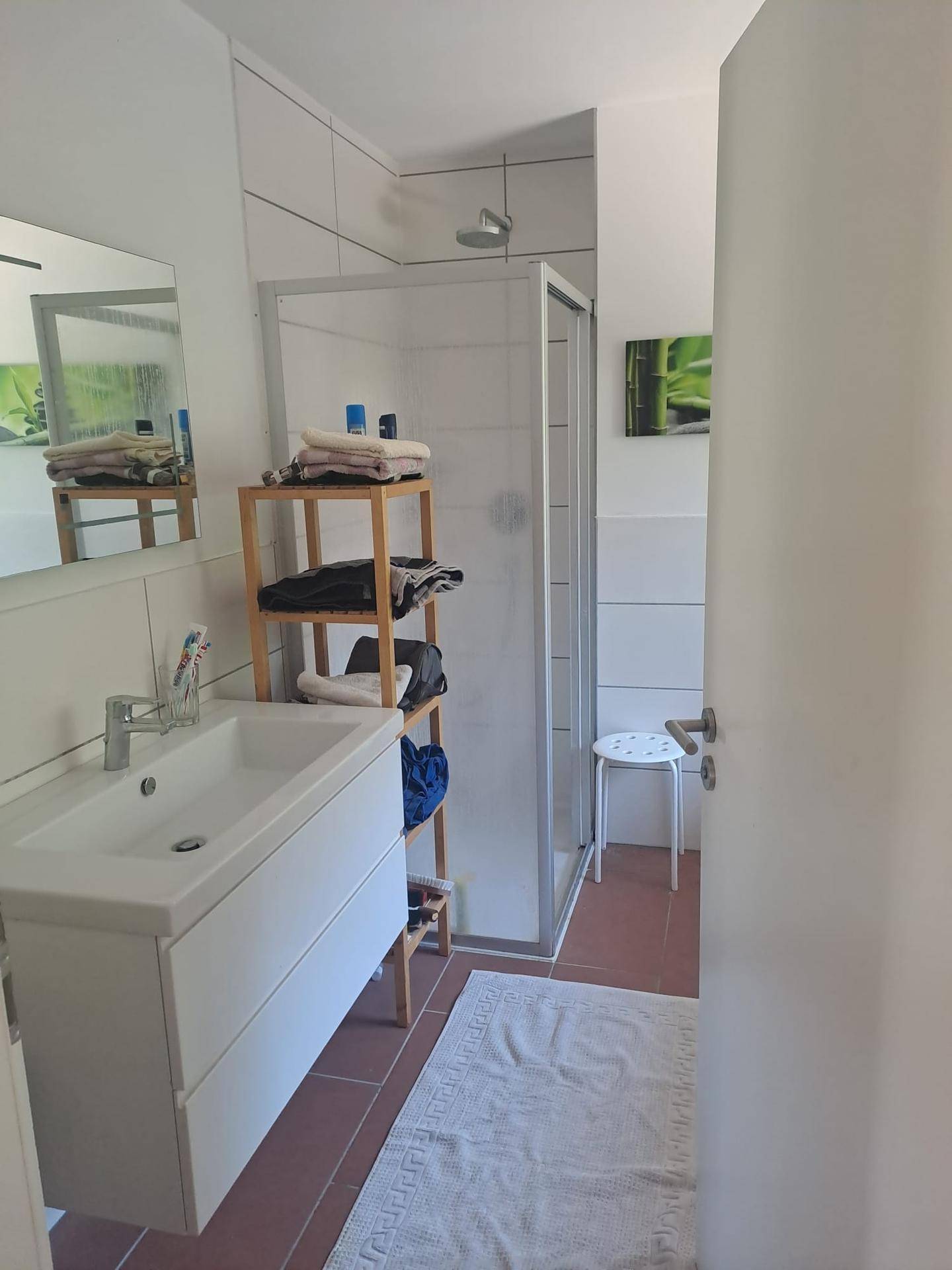 Modernes Badezimmer mit Duschkabine, Einzelwaschbecken und weißen Wandfliesen.