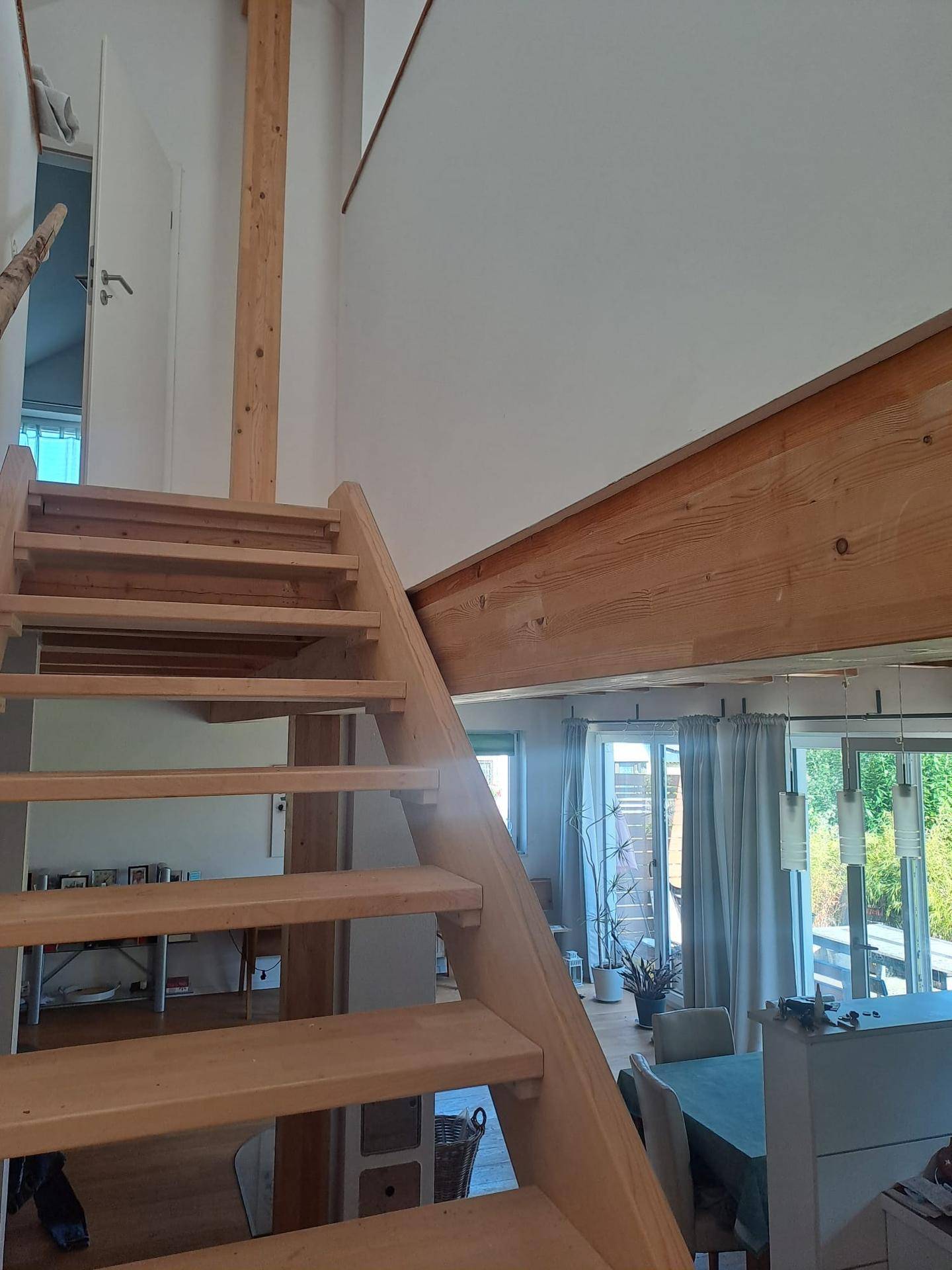 Offene Holztreppe führt in den oberen Bereich, mit Blick auf den Wohn-Essbereich.