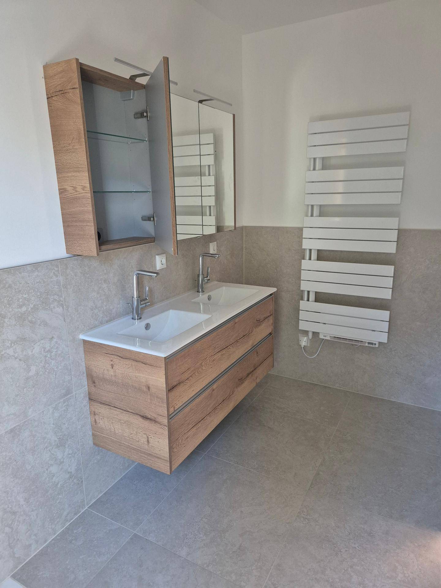 Modernes Badezimmer mit Doppelwaschbecken, Spiegelschrank und beheiztem Handtuchhalter.
