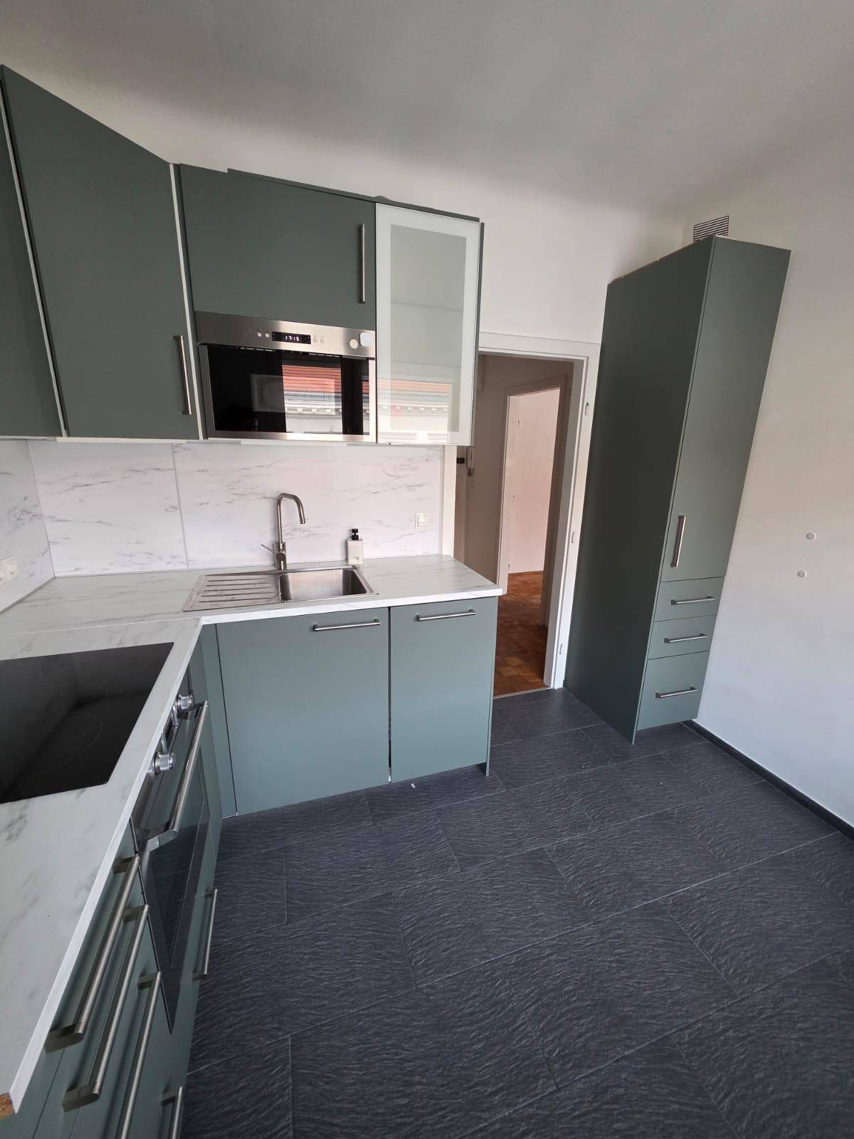 Funktionale Küche mit integriertem Backofen und Mikrowelle, sowie einem hohen Vorratsschrank.