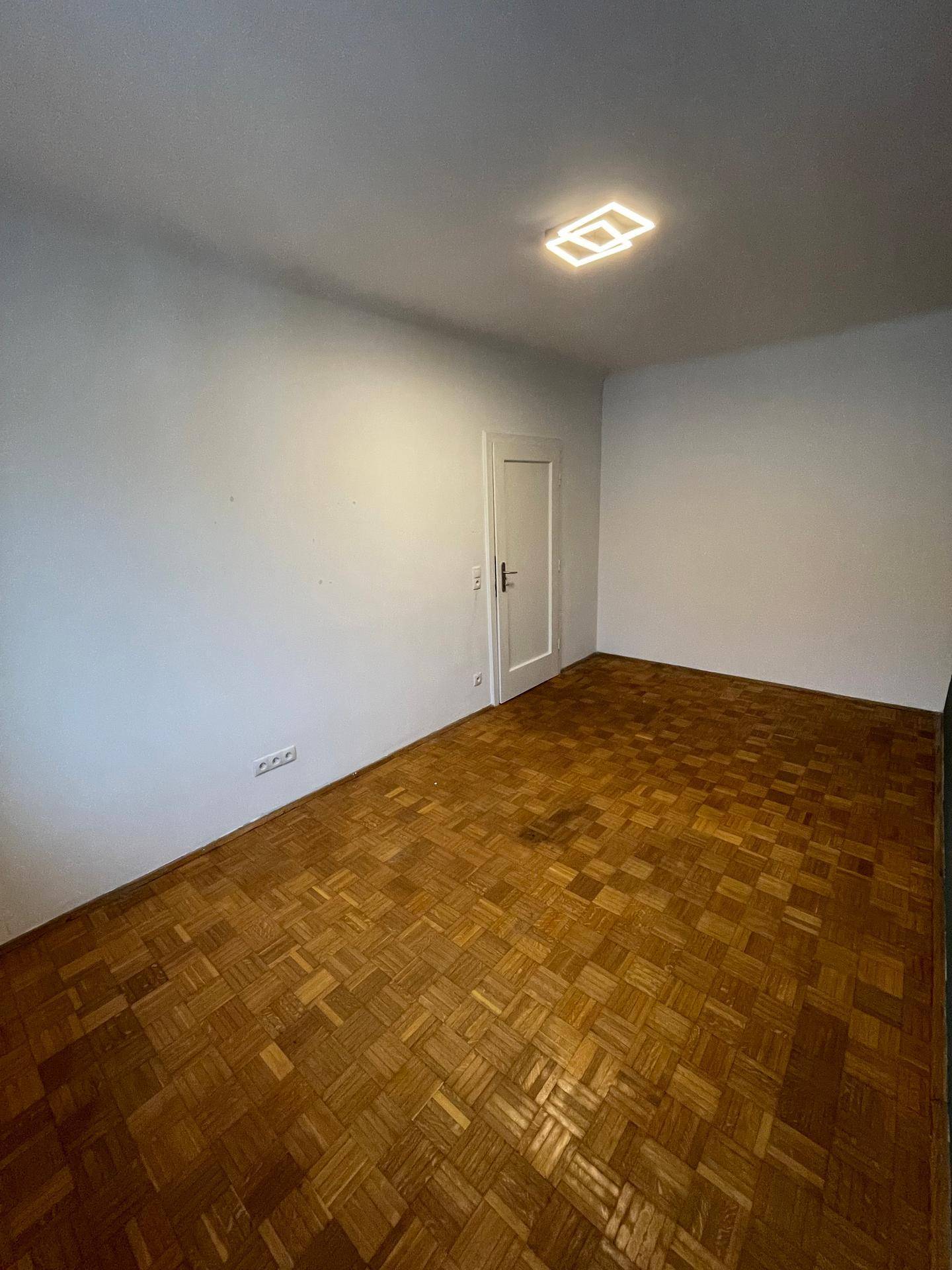 Leeres Schlafzimmer mit Parkettboden und weißen Wänden, bereit zur individuellen Gestaltung.