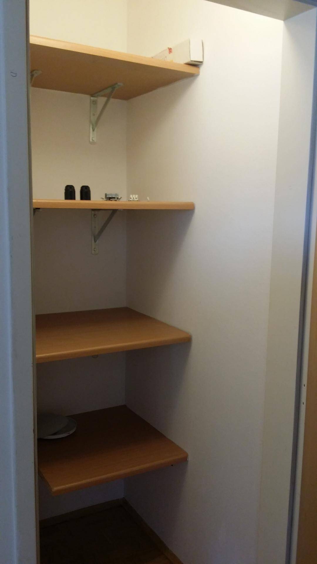 Praktischer Abstellraum mit mehreren Holzregalen für zusätzlichen Stauraum.