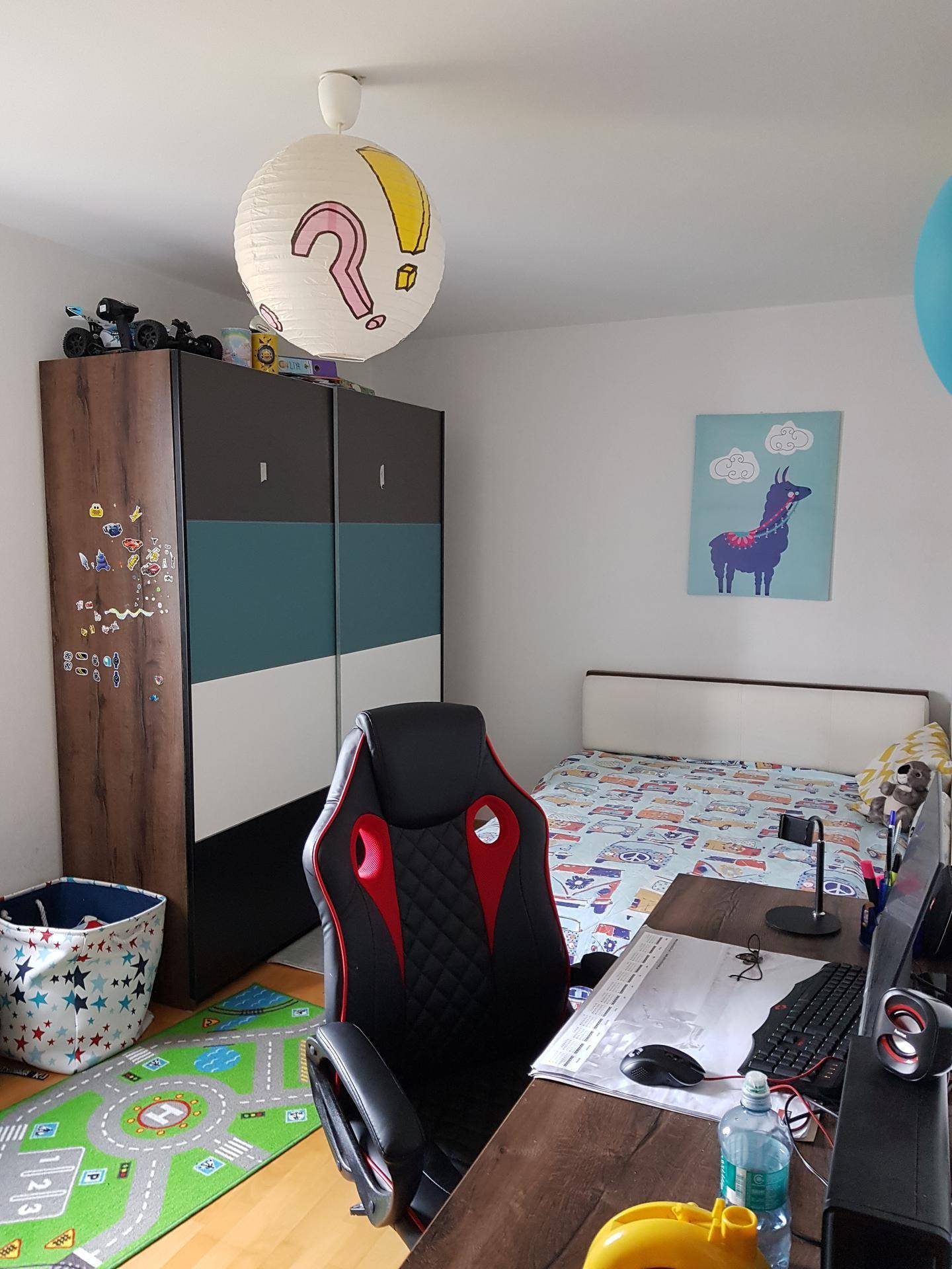 Kinderzimmer oder Arbeitszimmer mit Bett, Schreibtisch, Stuhl und einem bunten Kleiderschrank.