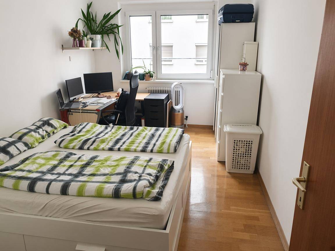 Helles Schlafzimmer mit Doppelbett, Schreibtisch, Stauraum und Blick aus dem Fenster.