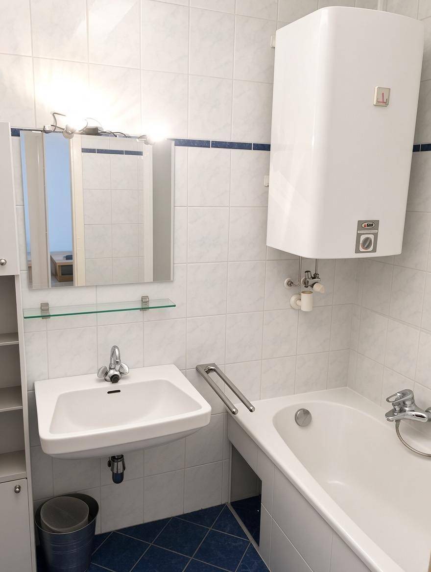 Badezimmer mit Waschbecken, Spiegel, Badewanne und einem Warmwasserboiler an der Wand.
