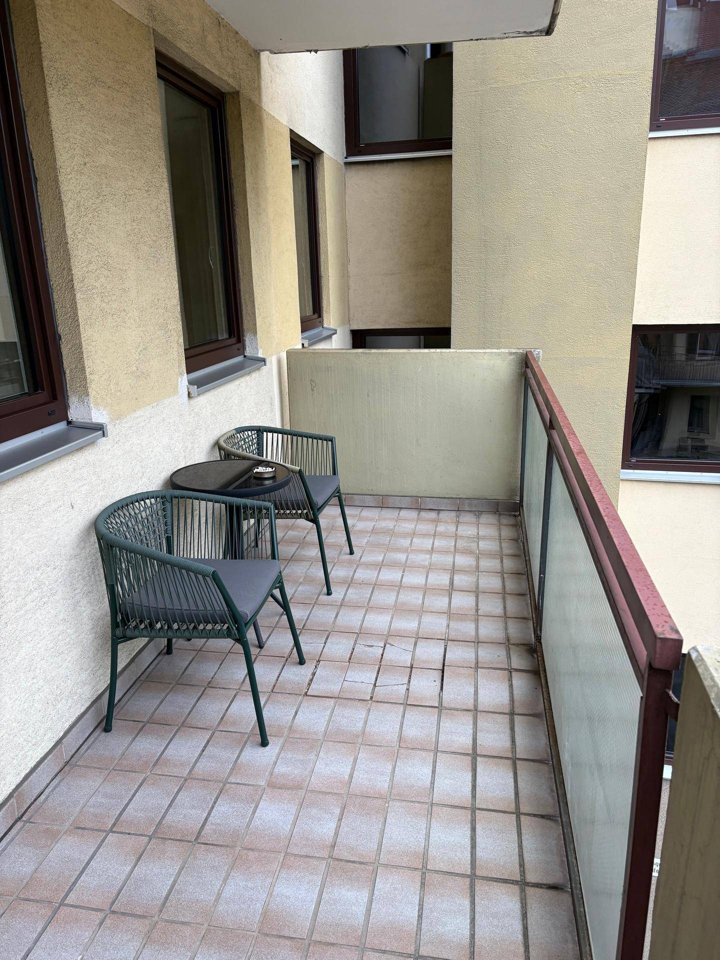 Kleiner Balkon mit Fliesenboden, ausgestattet mit zwei Stühlen und einem Tisch für entspannte Stunden.