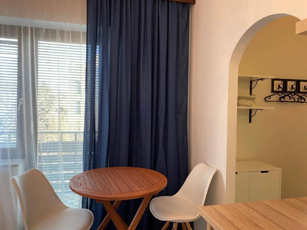 Gemütlicher Essbereich mit kleinem Holztisch und Stühlen neben einem Fenster mit blauen Vorhängen.