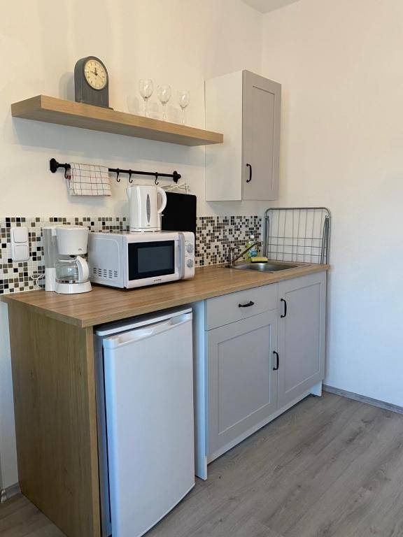 Kompakte Küchenzeile mit Mikrowelle, Kühlschrank, Spüle und Holzarbeitsplatte, ideal für kleine Wohnungen.