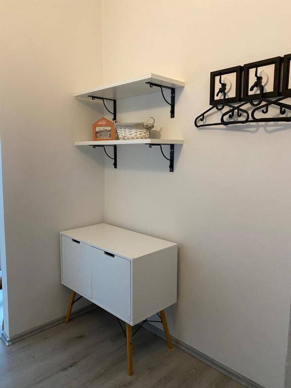 Einfacher Flurbereich mit einem weißen Schrank, Wandregalen und einer Garderobe für zusätzlichen Stauraum.