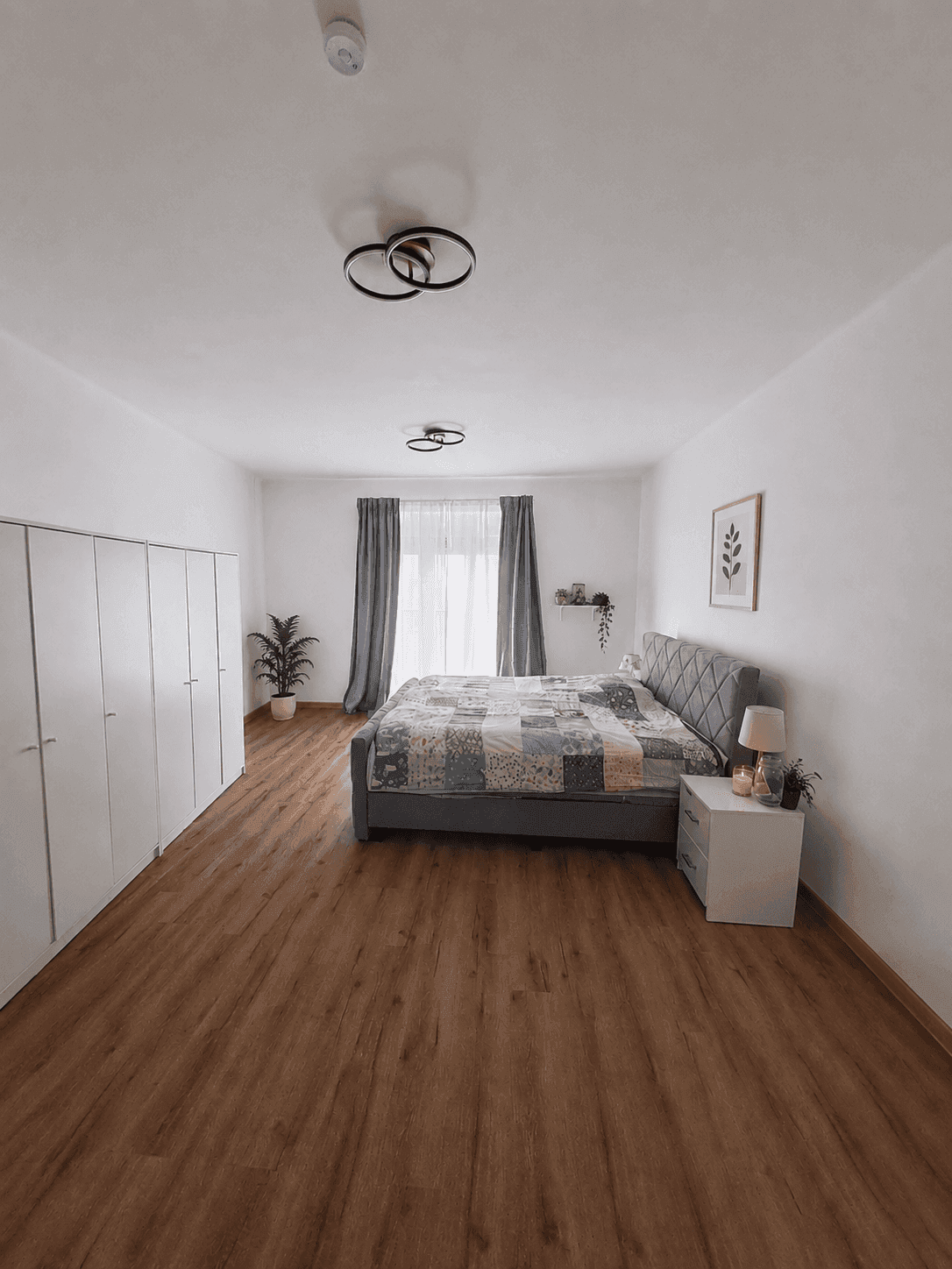 Geräumiges Schlafzimmer mit Doppelbett, weißen Kleiderschränken und Holzboden.