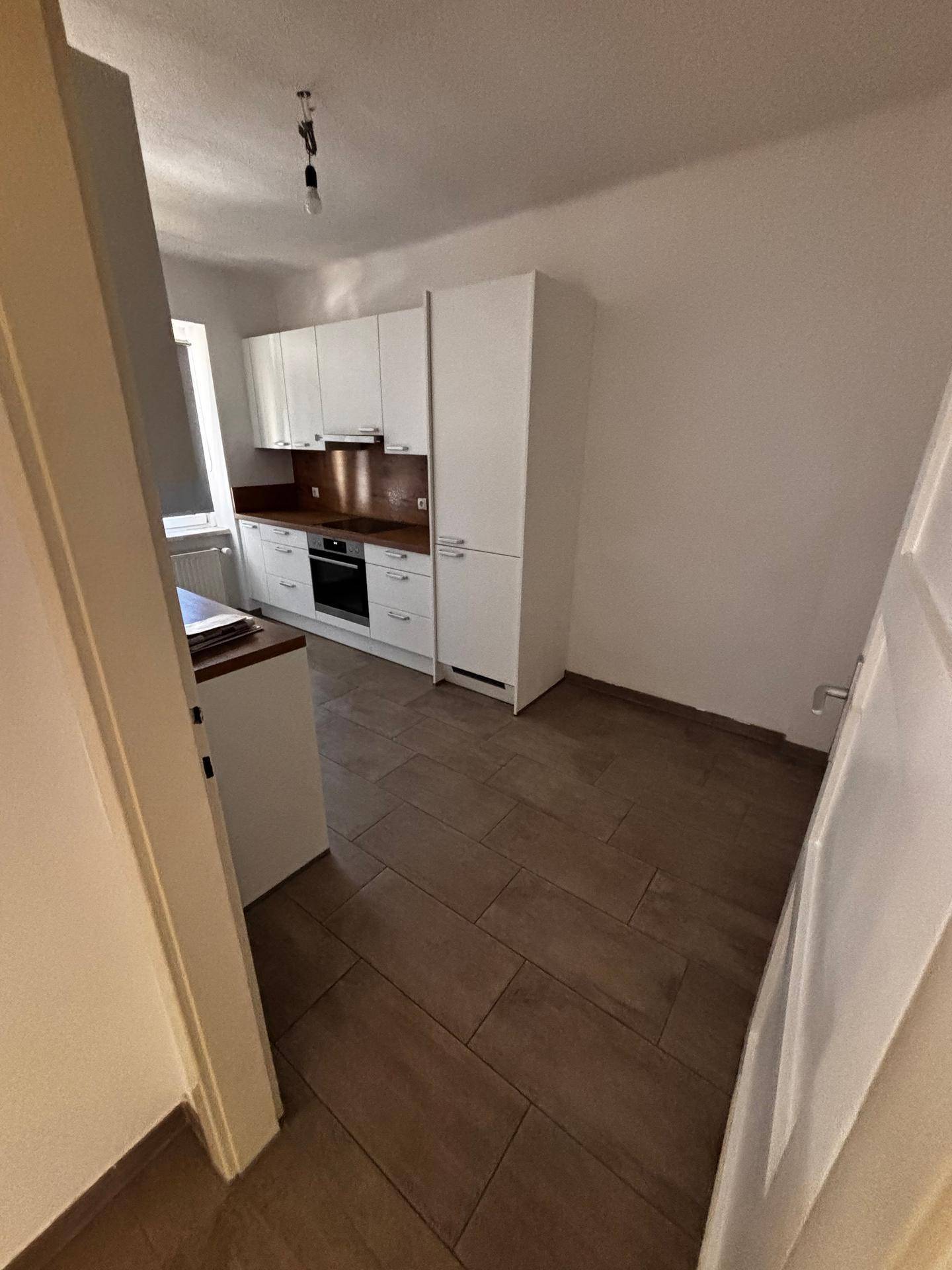 Moderne Küche mit weißen Schränken, Holzarbeitsplatten und integriertem Backofen.