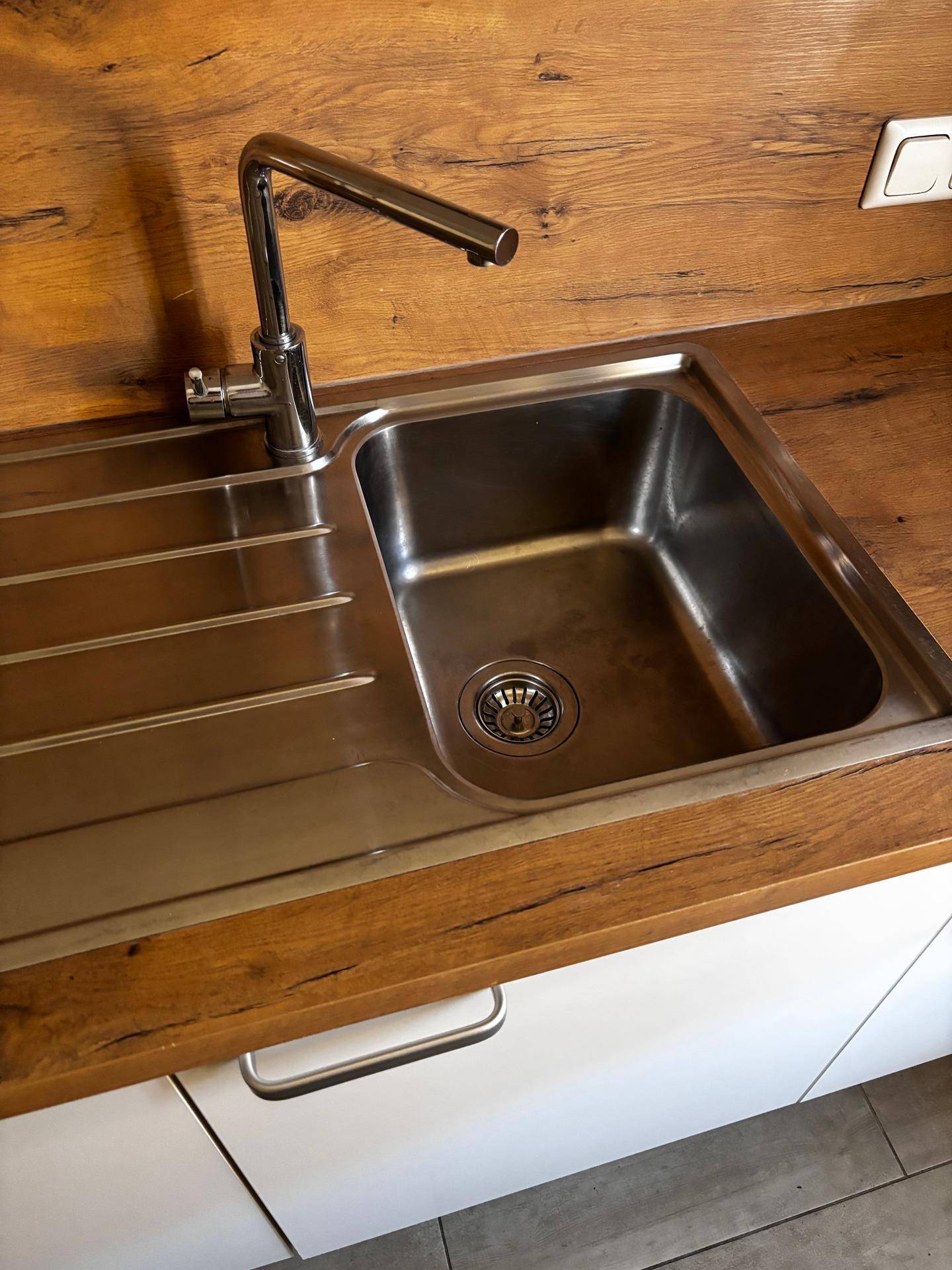 Edelstahlspüle mit modernem Wasserhahn und Abtropffläche in der Küche.