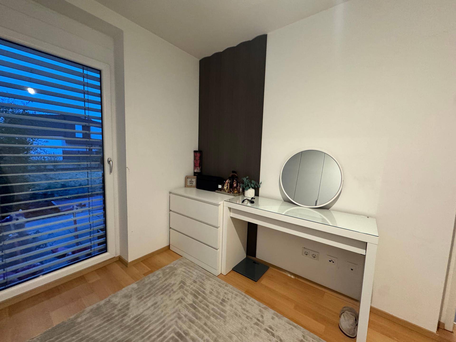 Schminktisch mit Spiegel und Fenster mit Jalousien im Schlafzimmer.