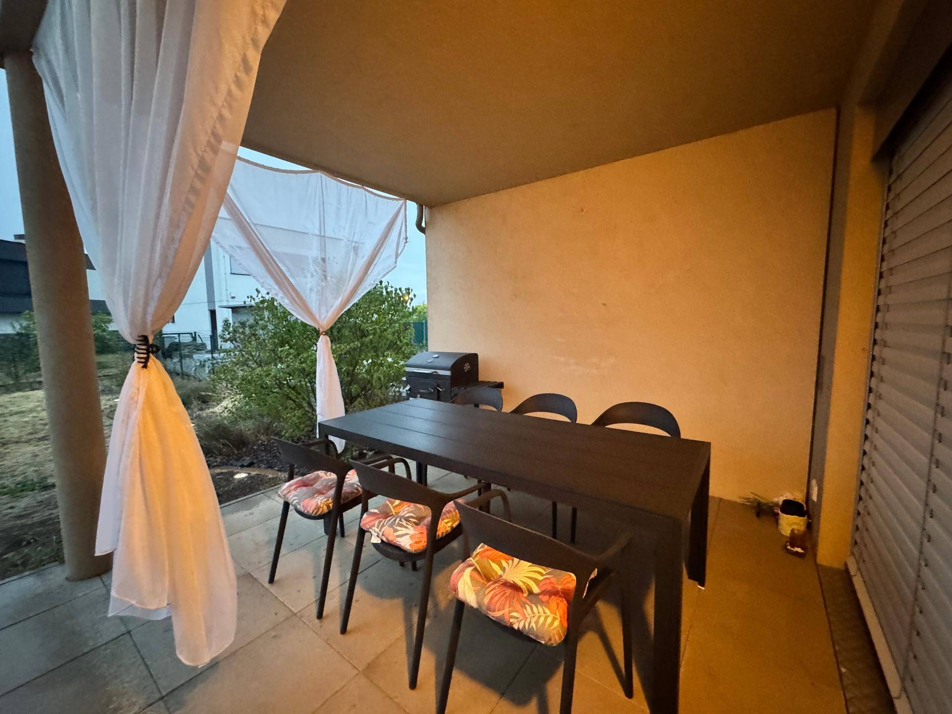 Überdachte Terrasse mit Esstisch, Stühlen und Vorhängen für Privatsphäre.