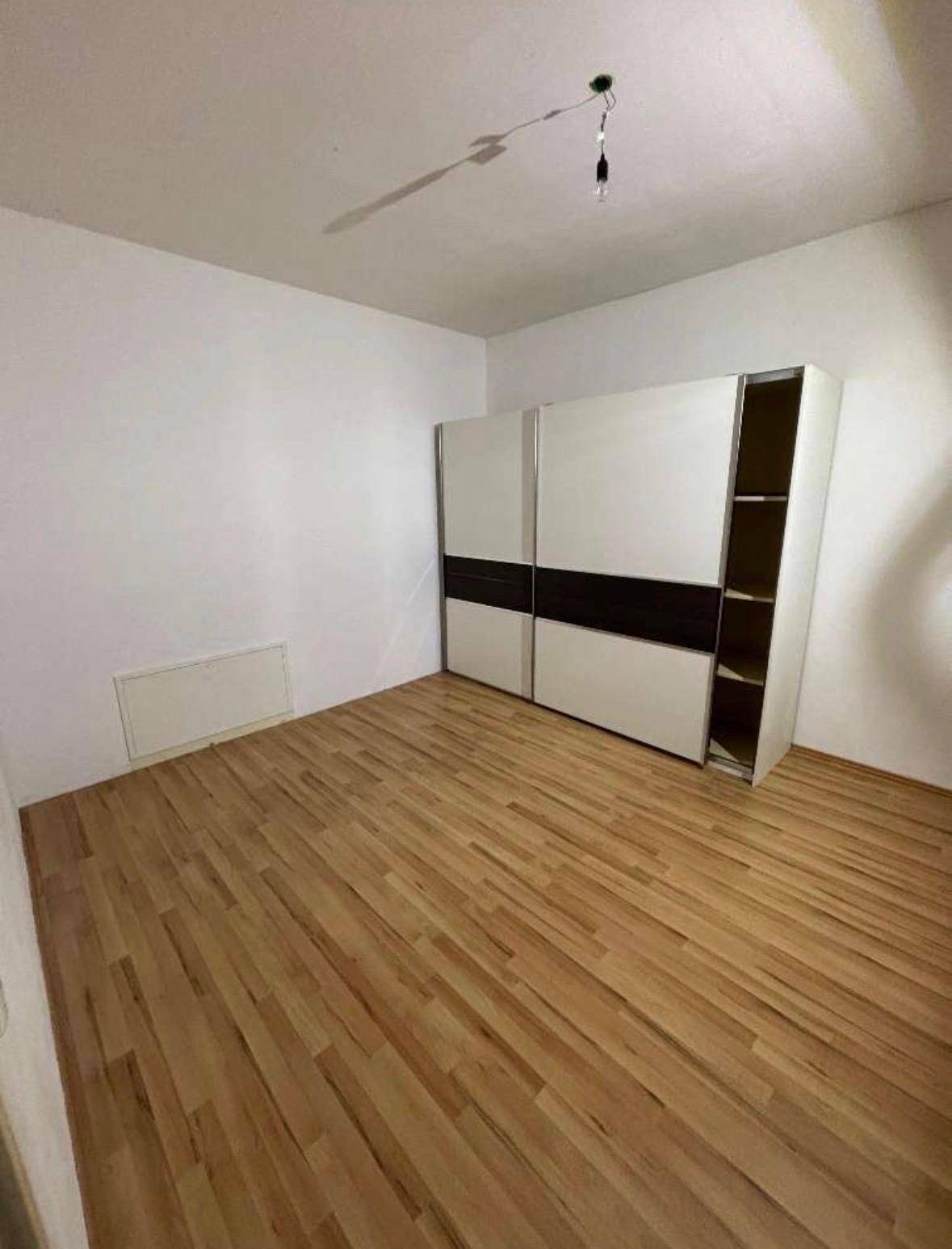 Geräumiges Schlafzimmer mit Holzboden und einem großen, modernen Kleiderschrank.