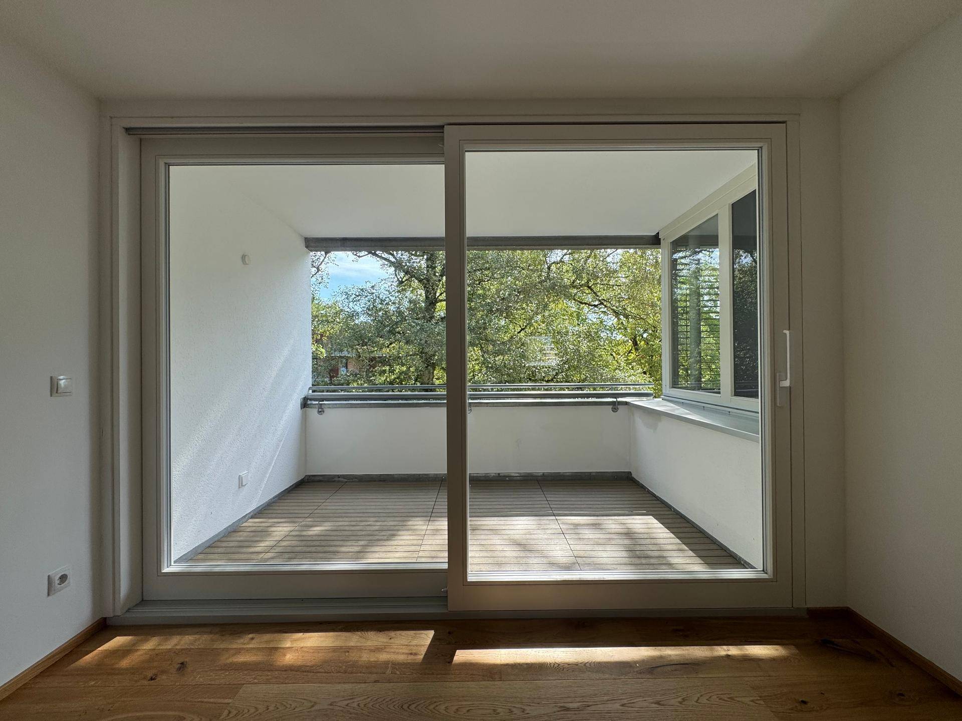 Heller Wohnraum mit großem Schiebefenster und direktem Zugang zu einem Balkon.