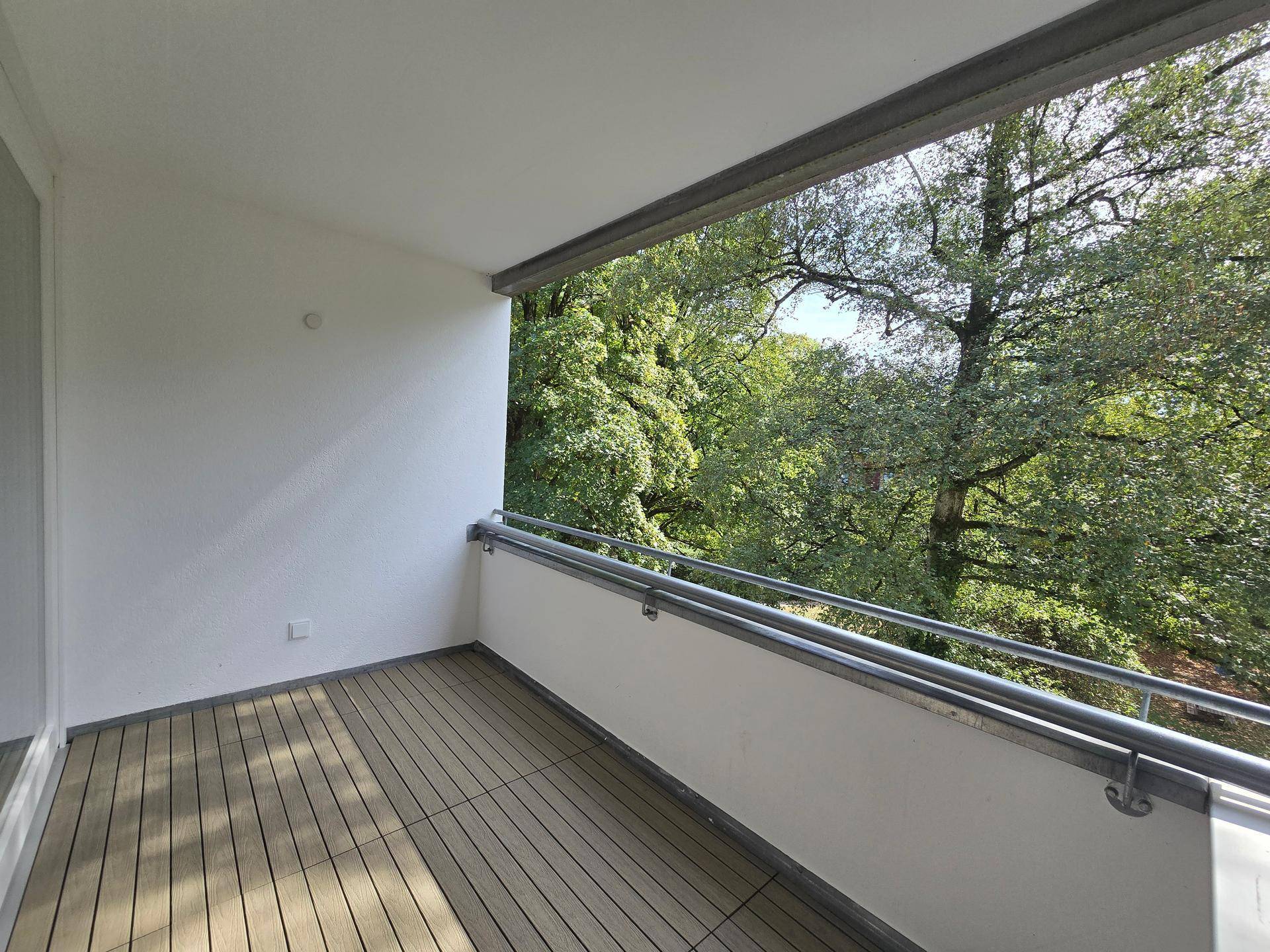 Geräumiger Balkon mit Holzboden und Blick ins Grüne, ideal zum Entspannen.