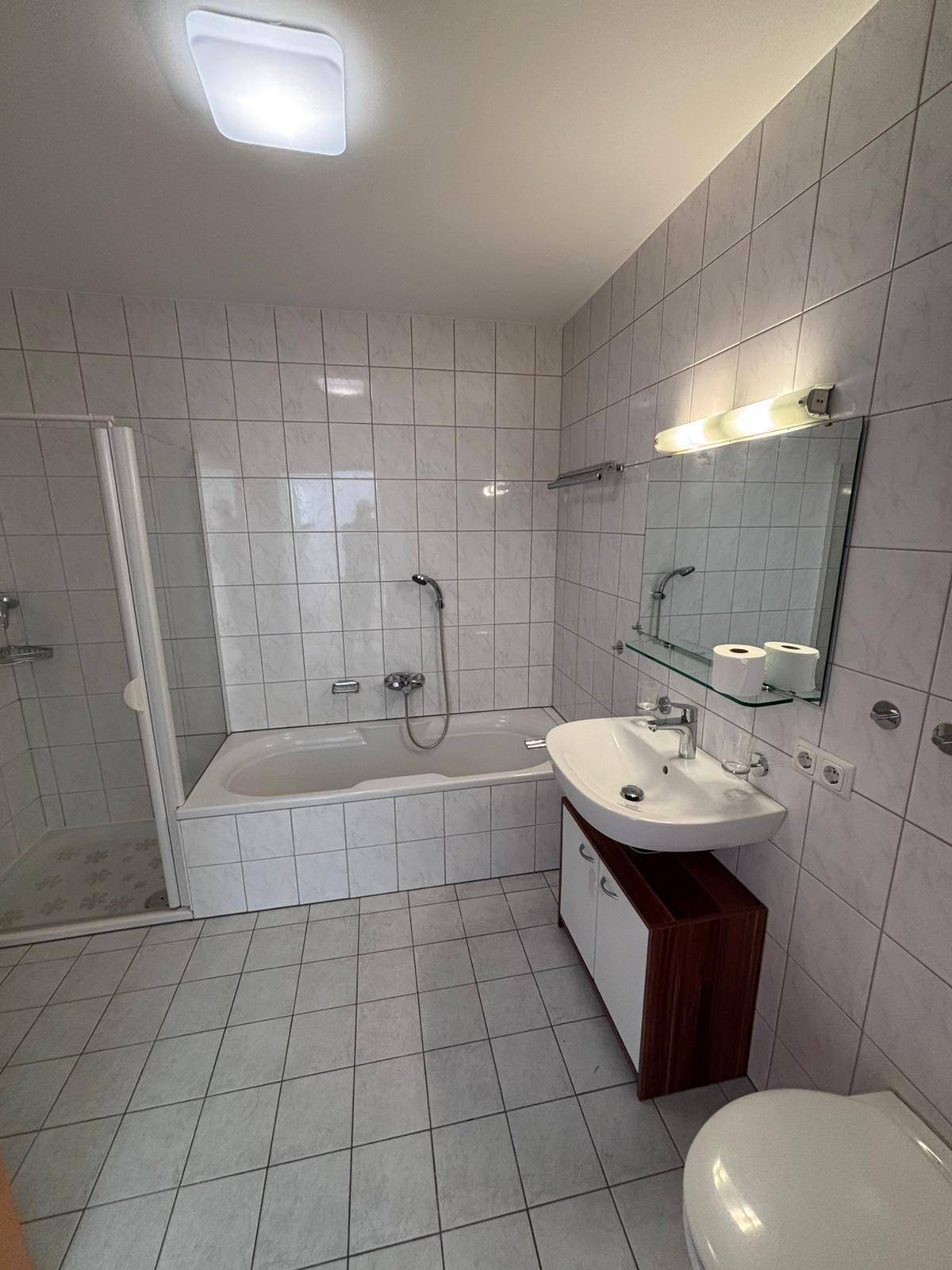 Gefliestes Badezimmer mit Badewanne, Duschkabine und Einzelwaschbecken.