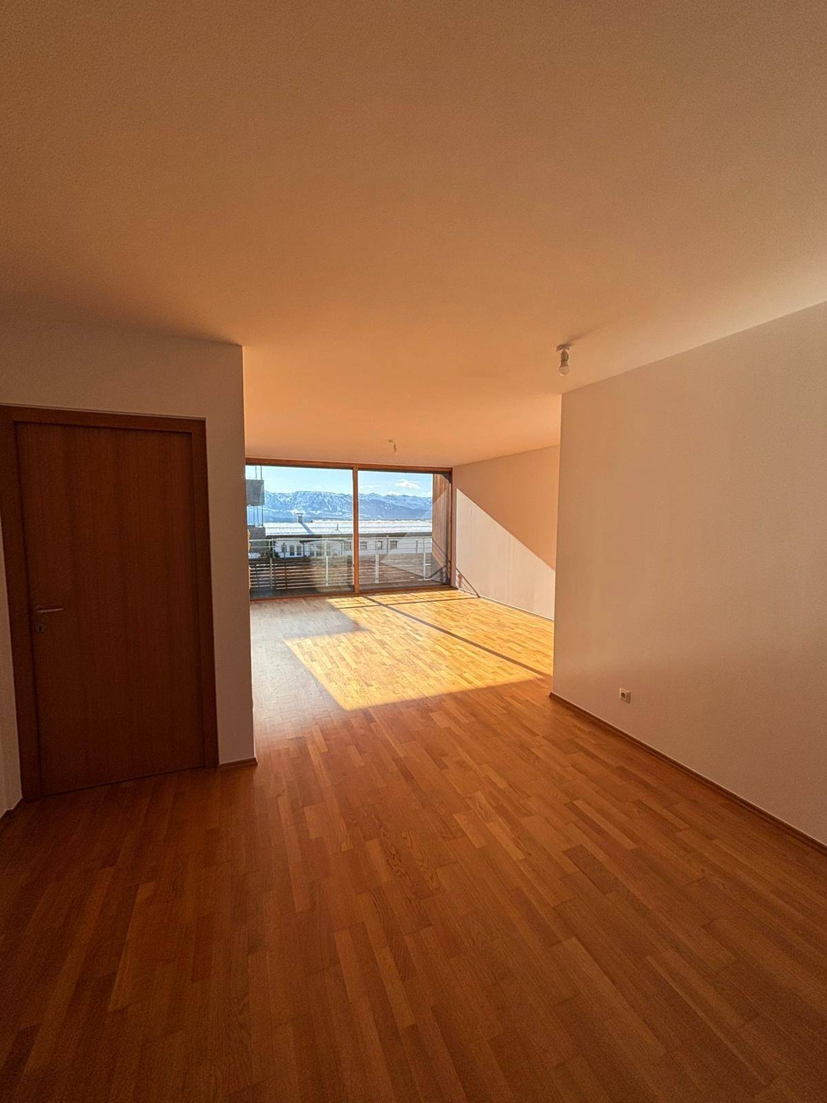 Helles Wohnzimmer mit großen Fenstern, Holzboden und weitem Blick auf die Landschaft.