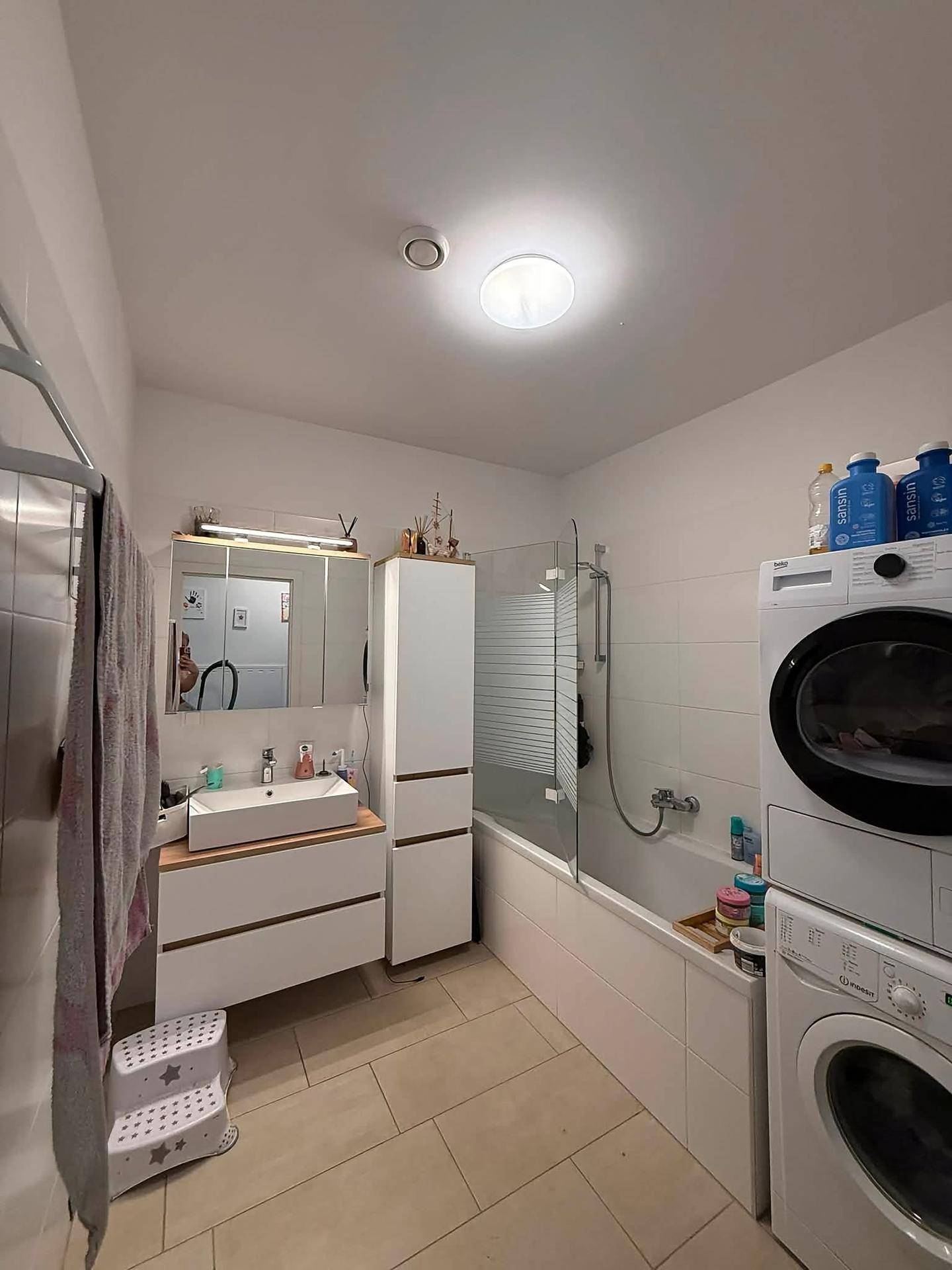 Modernes Badezimmer mit Badewanne, Duschabtrennung und integrierter Waschmaschine.