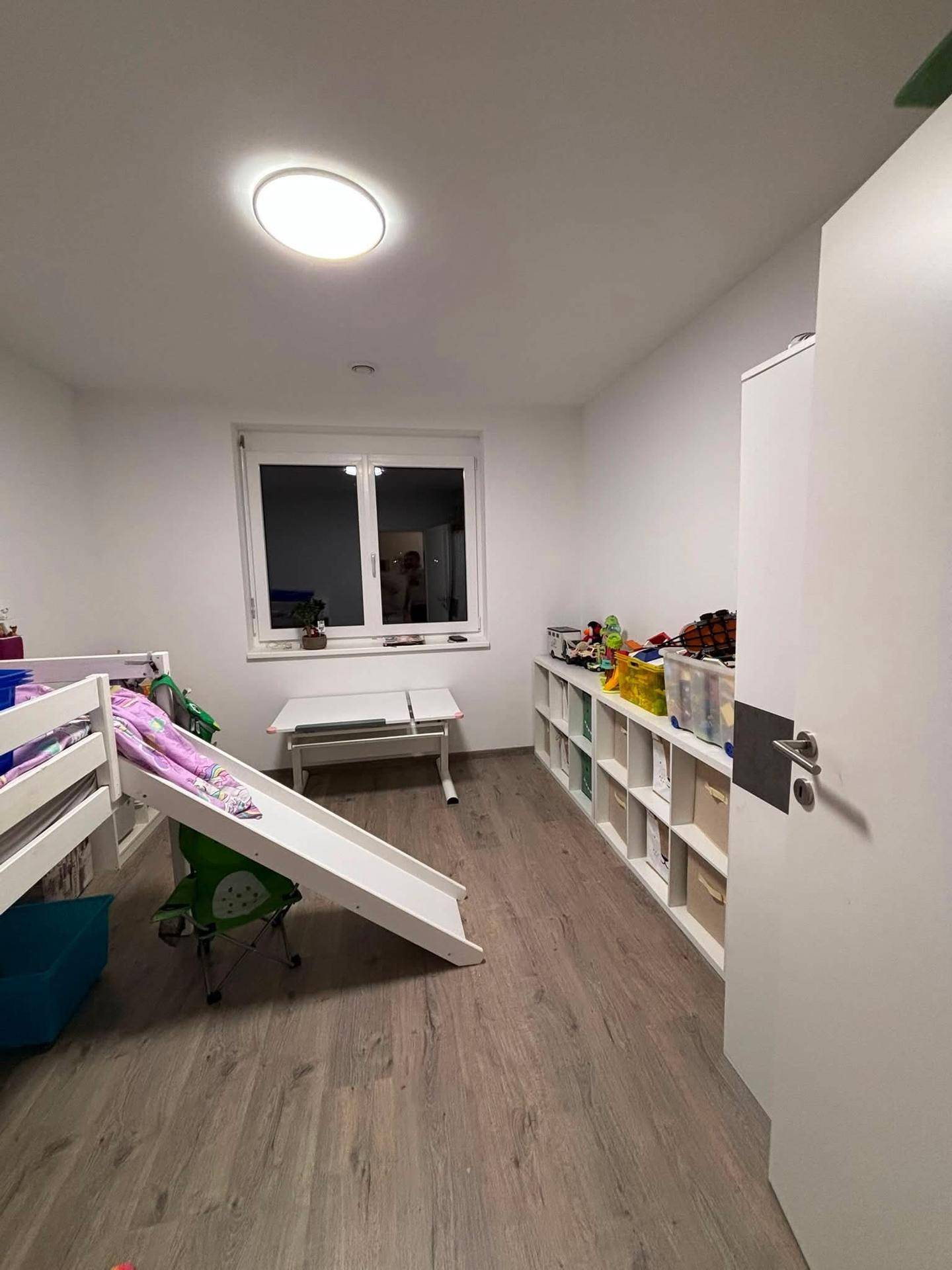 Kinderzimmer mit Hochbett, Rutsche und Regalen für Spielzeug.