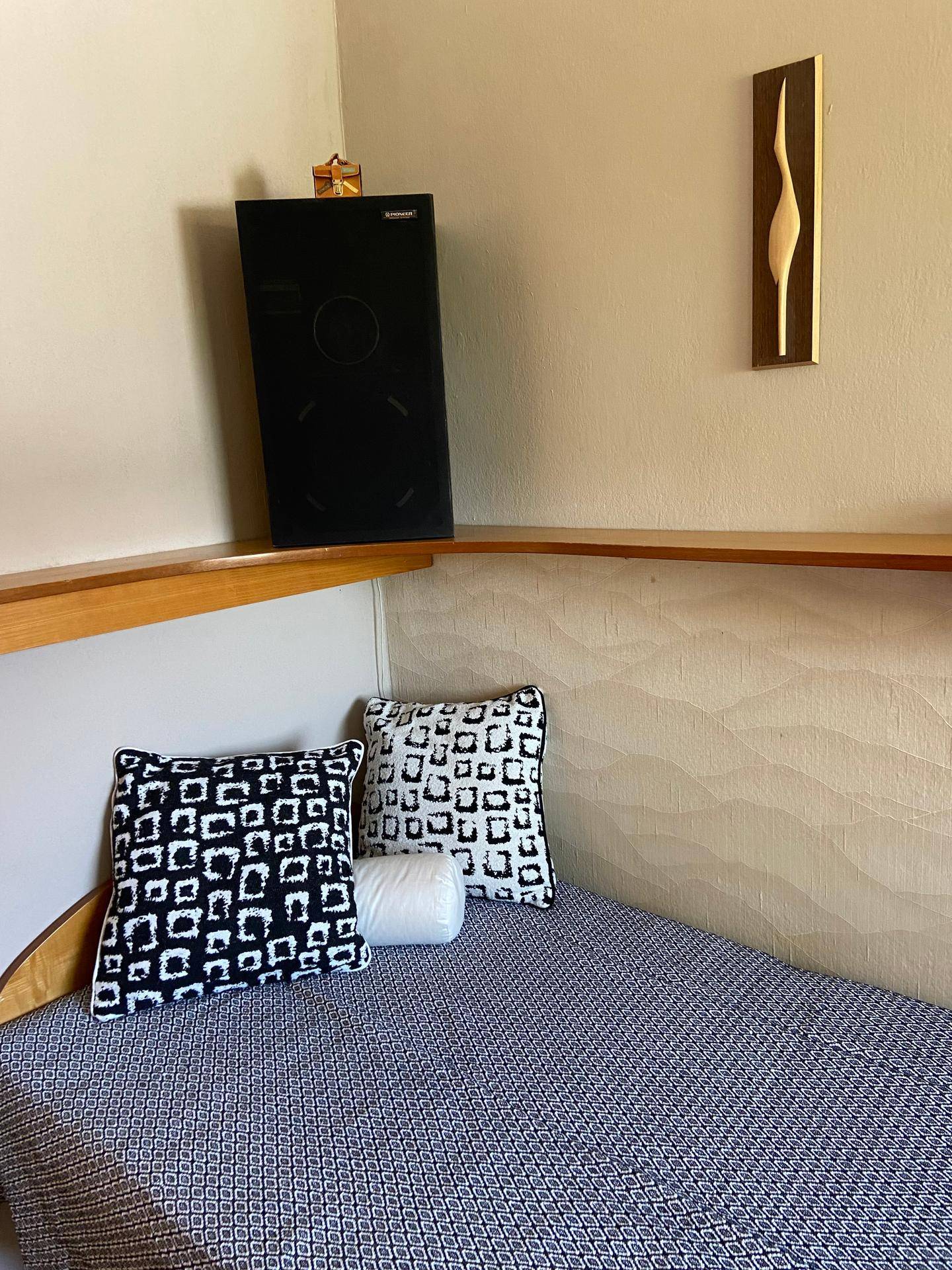 Gemütliche Ecke eines Schlafzimmers mit Bett, dekorativen Kissen und einem Lautsprecher.