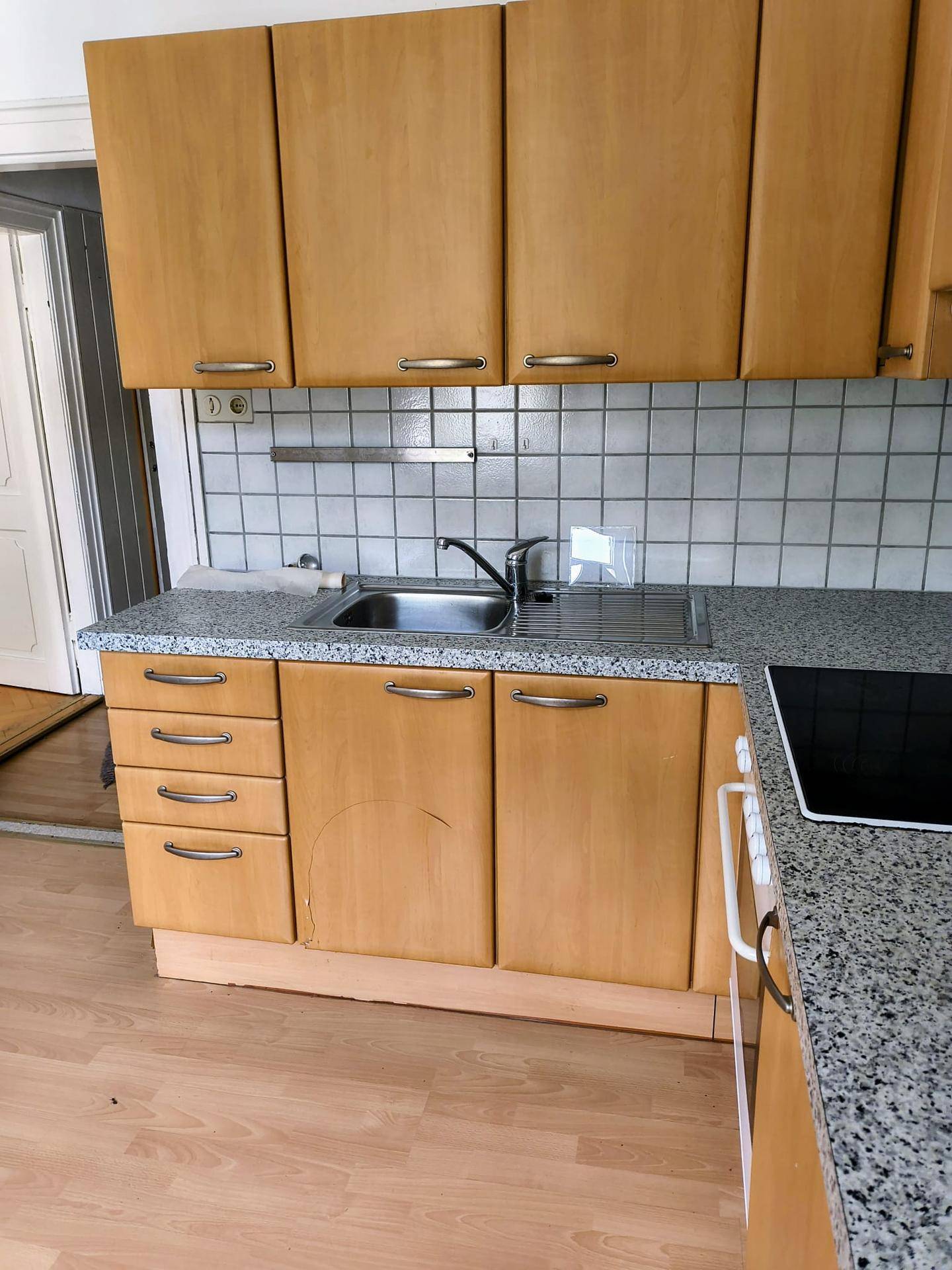 Helle Küche mit Holzschränken, Granitarbeitsplatte und Fliesenrückwand, bereit für den täglichen Gebrauch.