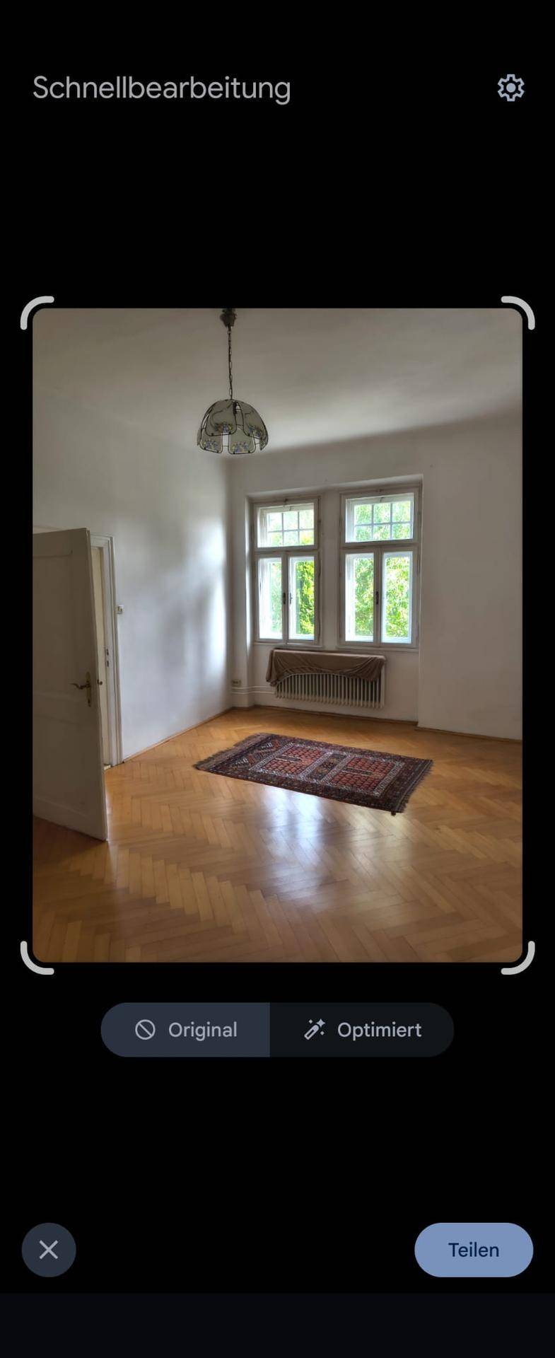 Geräumiger Raum mit Parkettboden, großem Fenster und einem Teppich, aufgenommen als Bildschirmfoto.