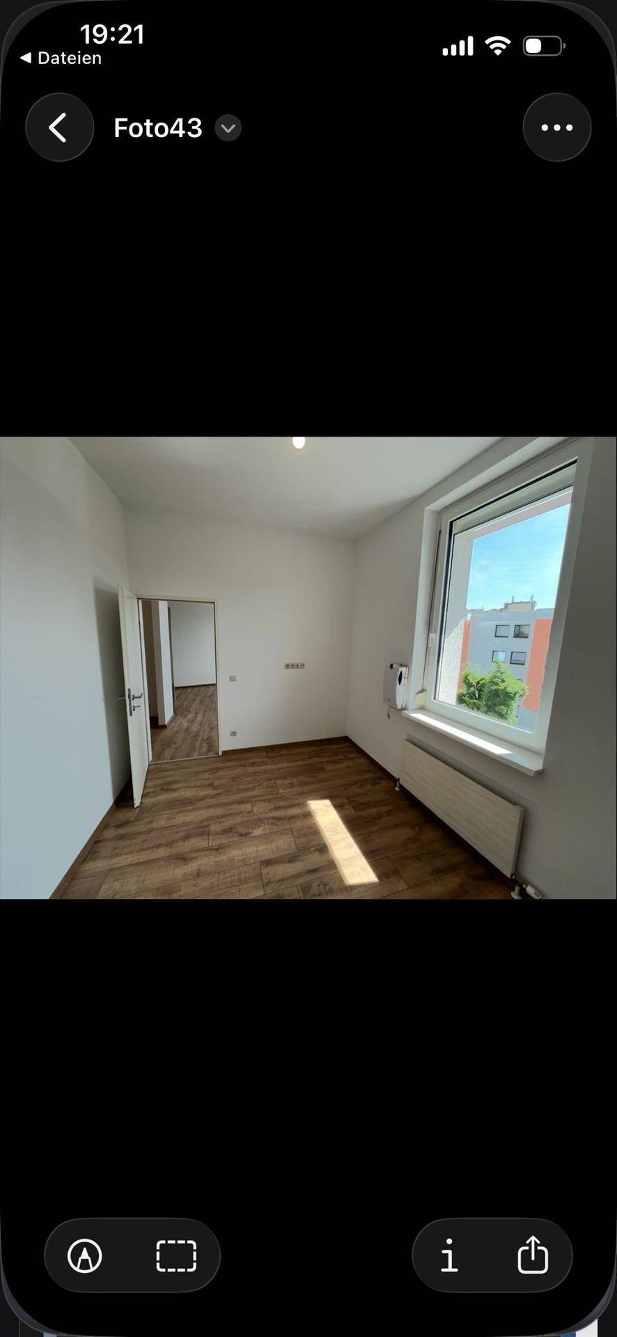 Leerer Raum mit Fenster, Heizkörper und Holzboden, bereit zur individuellen Gestaltung.