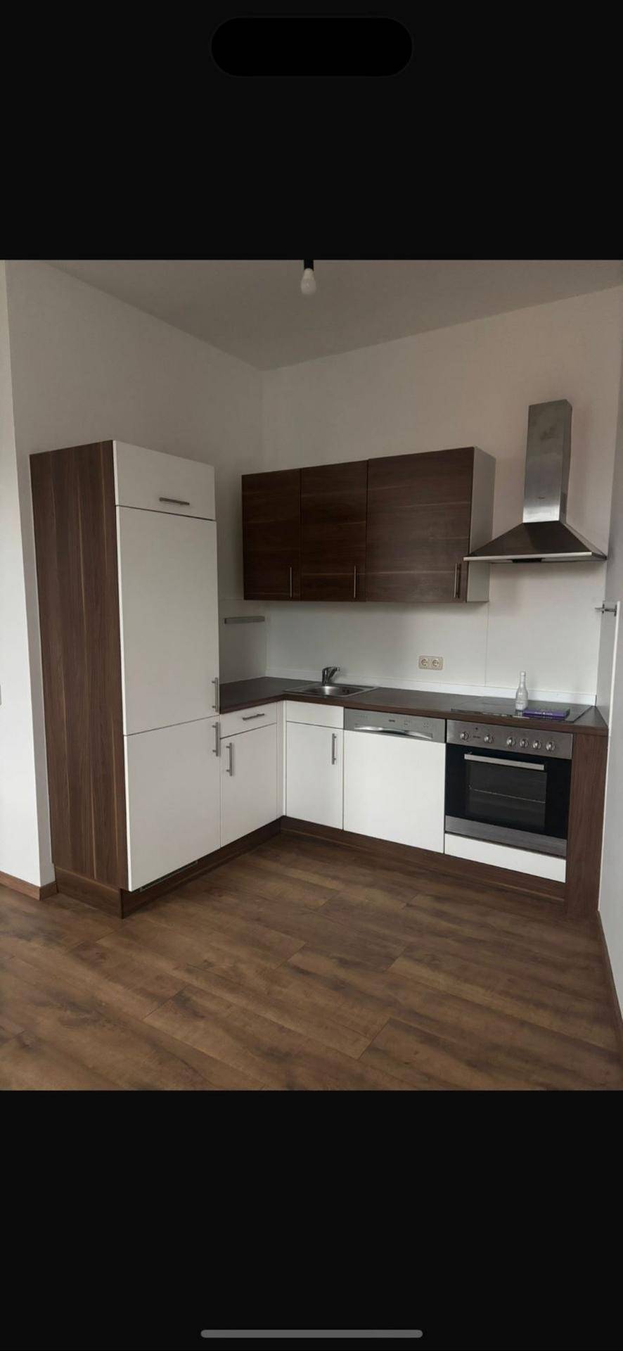 Moderne Einbauküche mit hellen und dunklen Holzfronten sowie integrierten Geräten.