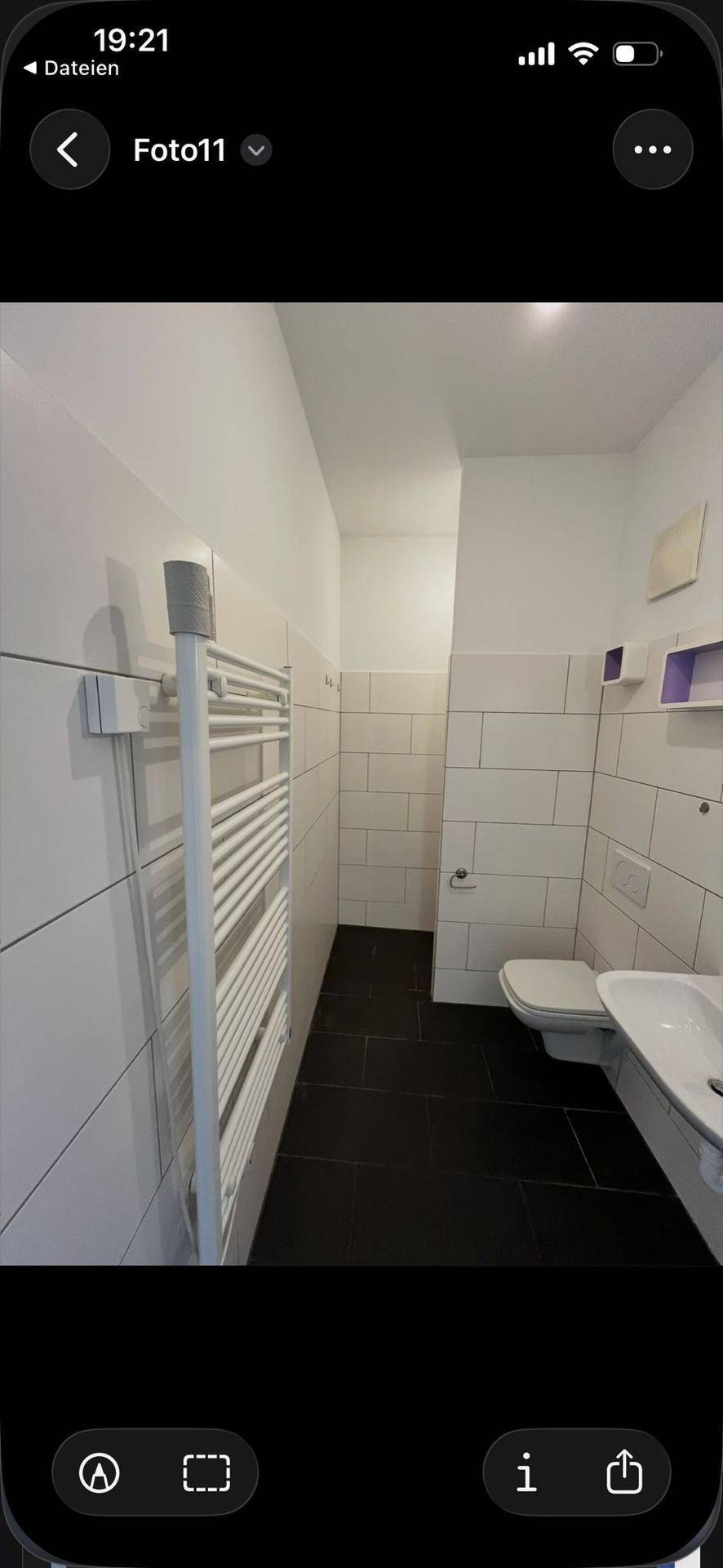 Helles Badezimmer mit WC, Waschbecken und praktischem Handtuchheizkörper an der Wand.
