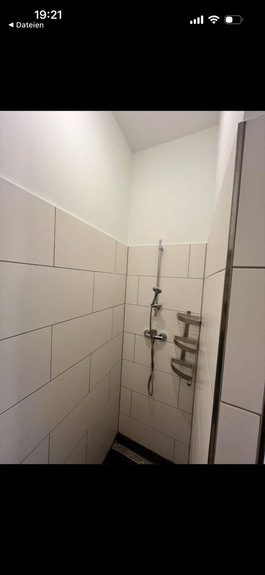 Duschbereich mit weißen Fliesen und moderner Duscharmatur in einem hellen Badezimmer.