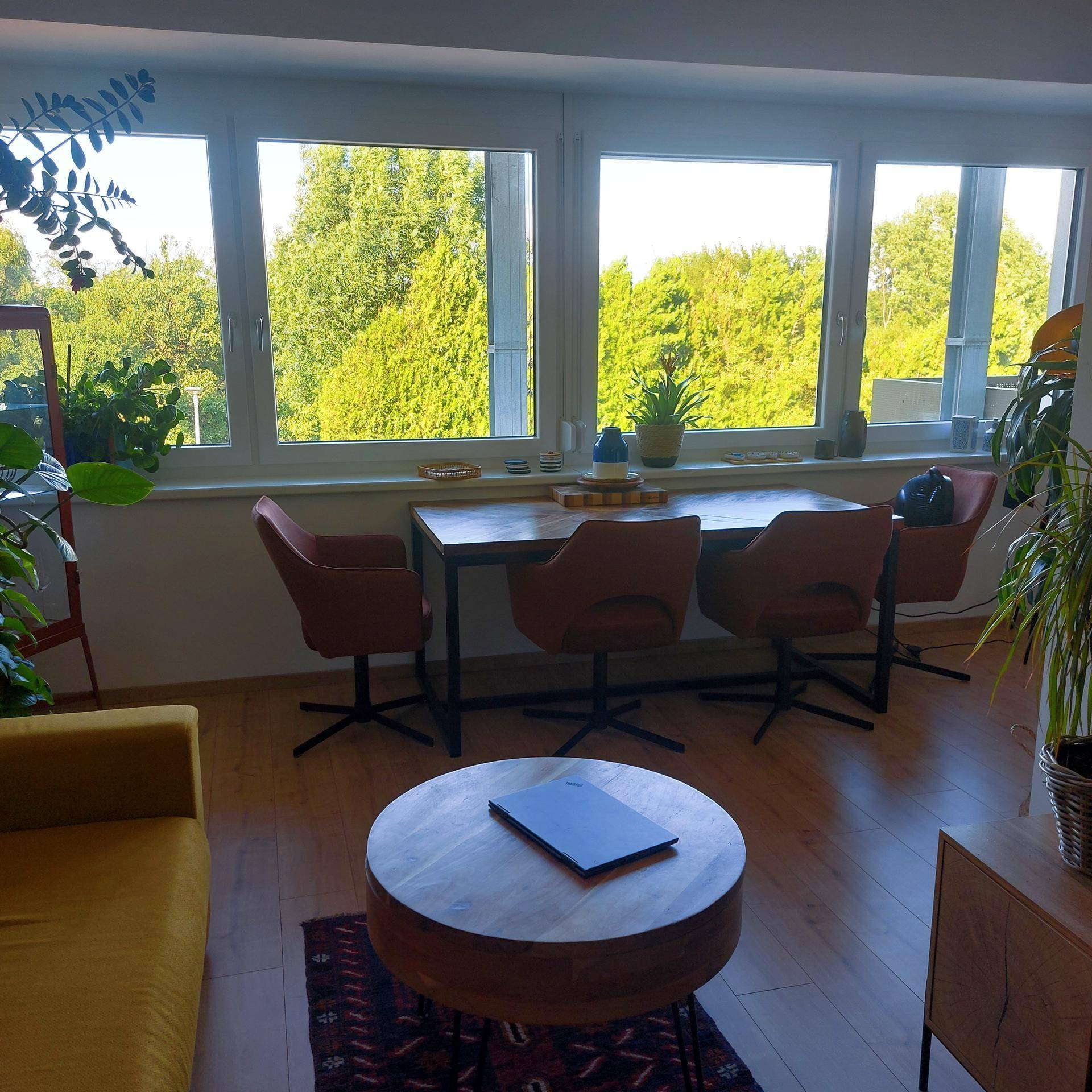 Kombinierter Wohn- und Essbereich mit großen Fenstern und Blick ins Grüne.