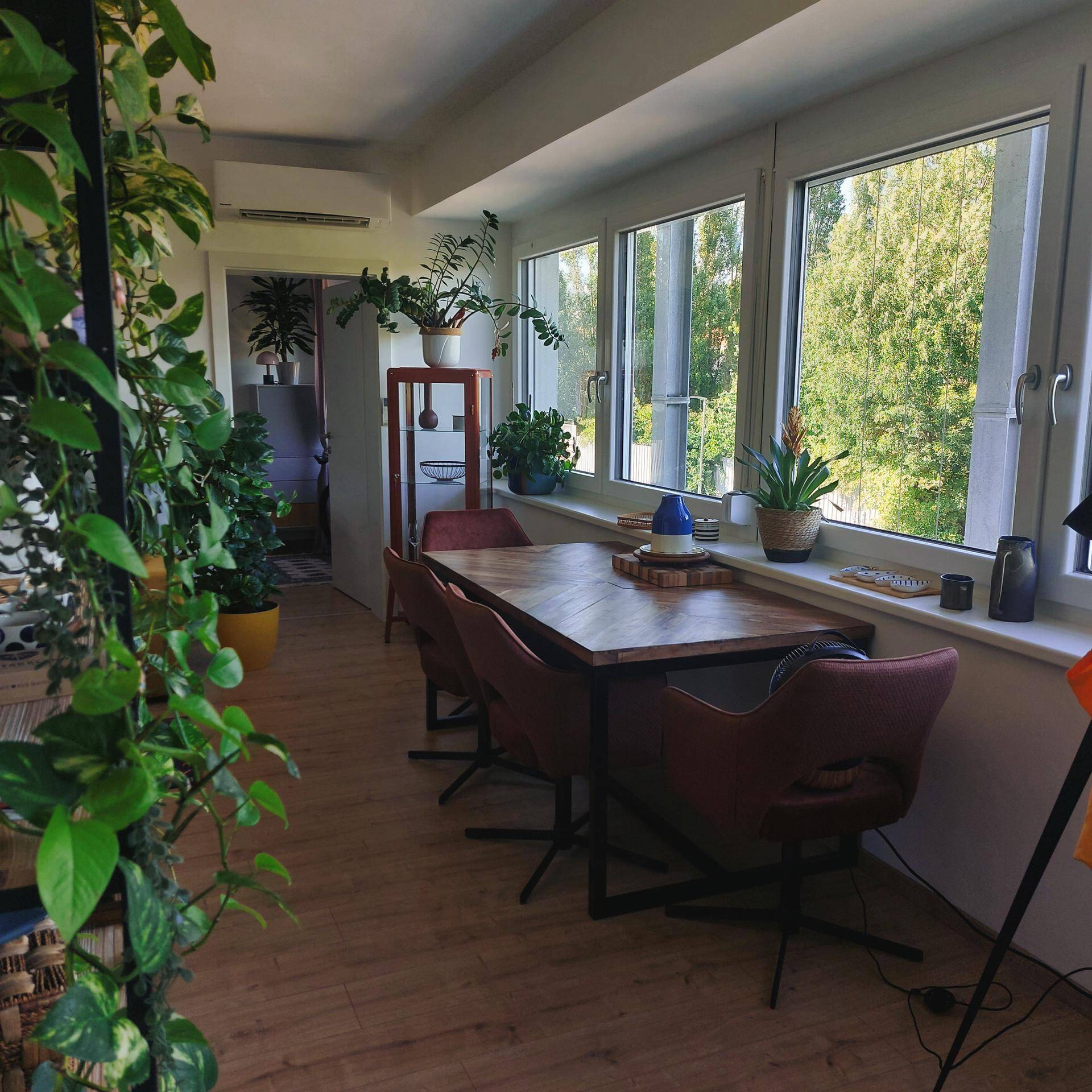 Heller Essbereich mit Holztisch, modernen Stühlen und großen Fenstern mit grüner Aussicht.