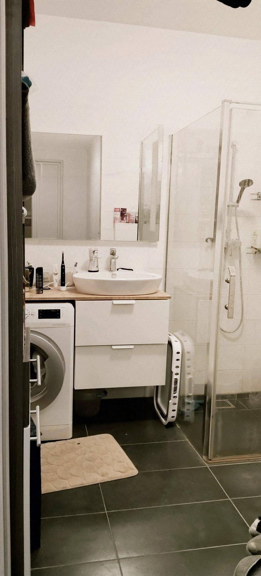Modernes Badezimmer mit Duschkabine, Waschbeckenunterschrank und Waschmaschine.