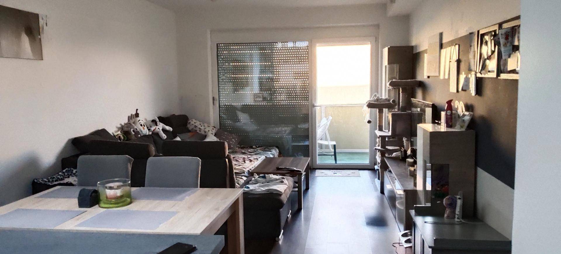 Heller Wohn- und Essbereich mit Zugang zum Balkon und moderner Einrichtung.